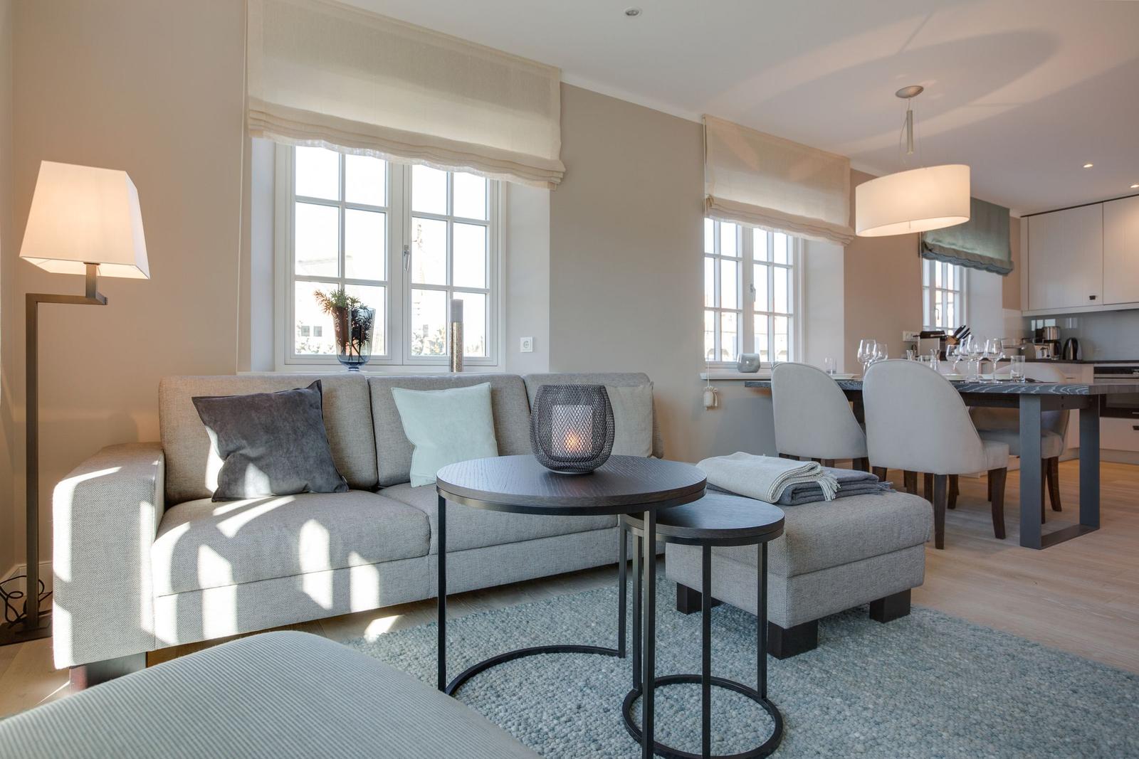 Living and dining area with sofa, table, and windows.