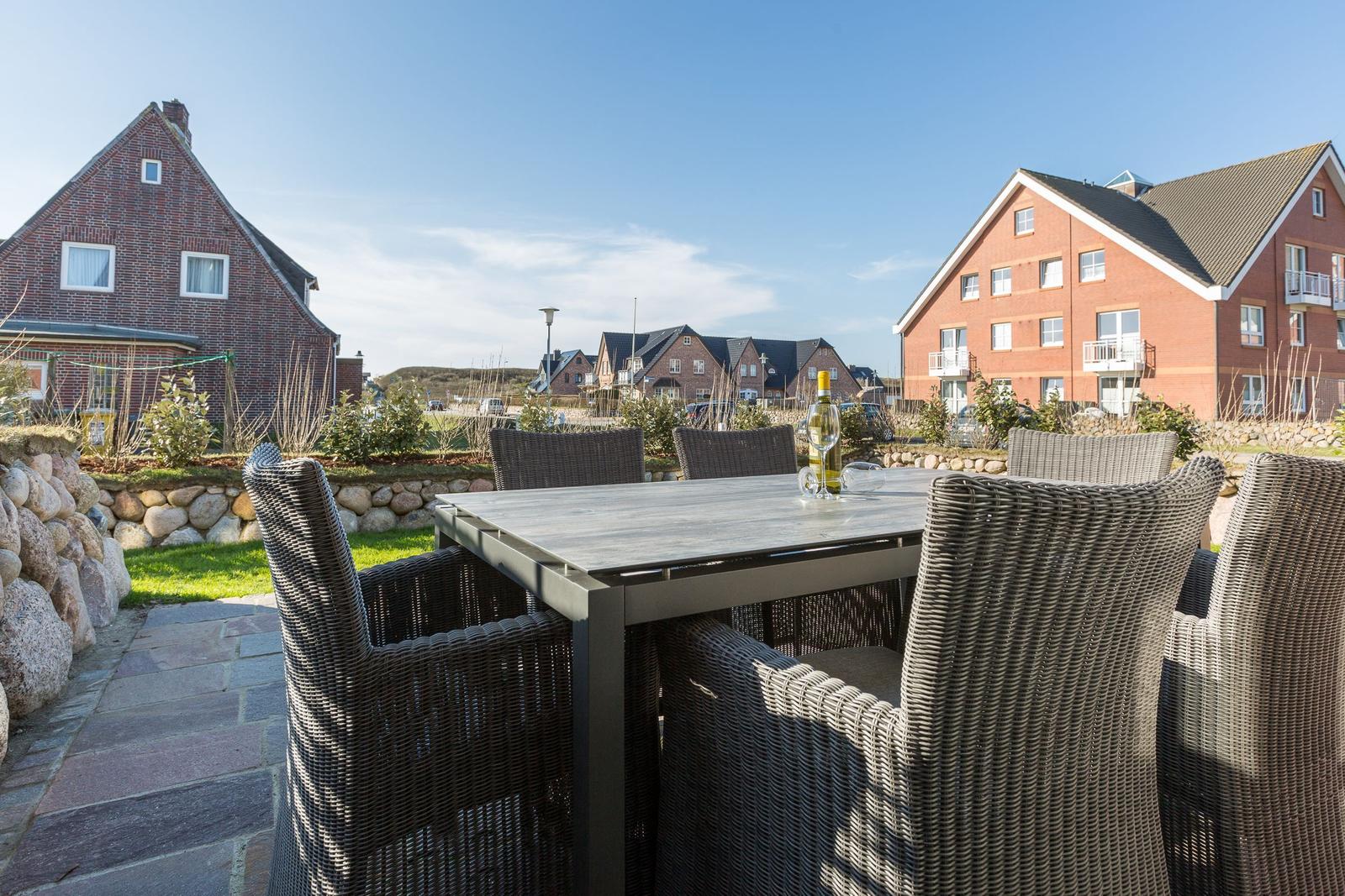 Terrace with table and chairs, view of houses and green areas.