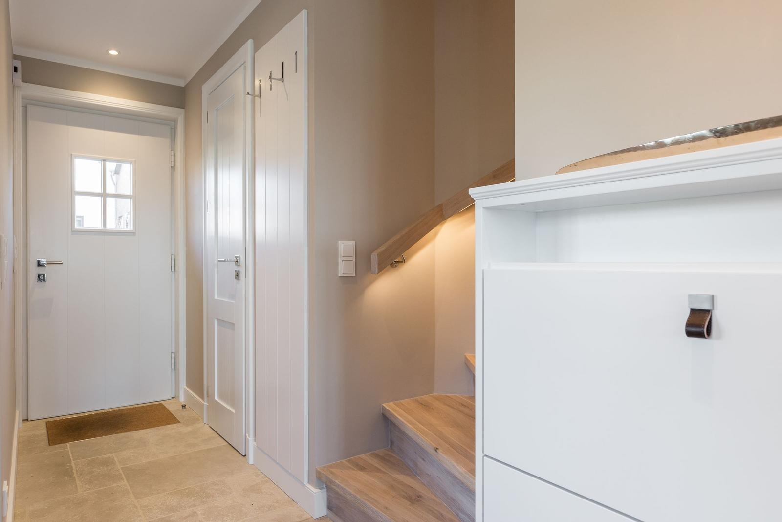 Entrance area with stairs, white doors, and wooden steps.
