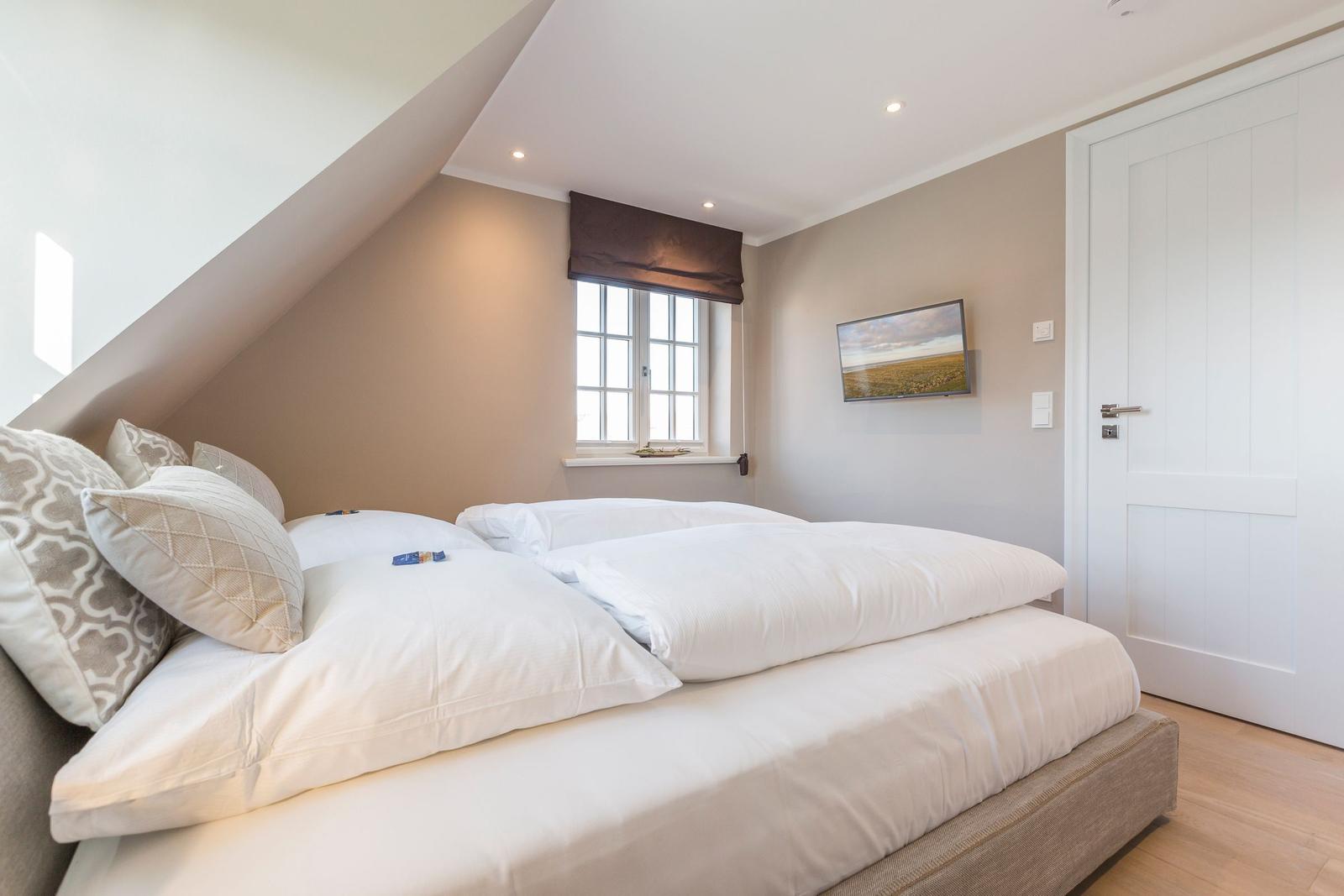Bedroom with double bed, window, and wall picture.