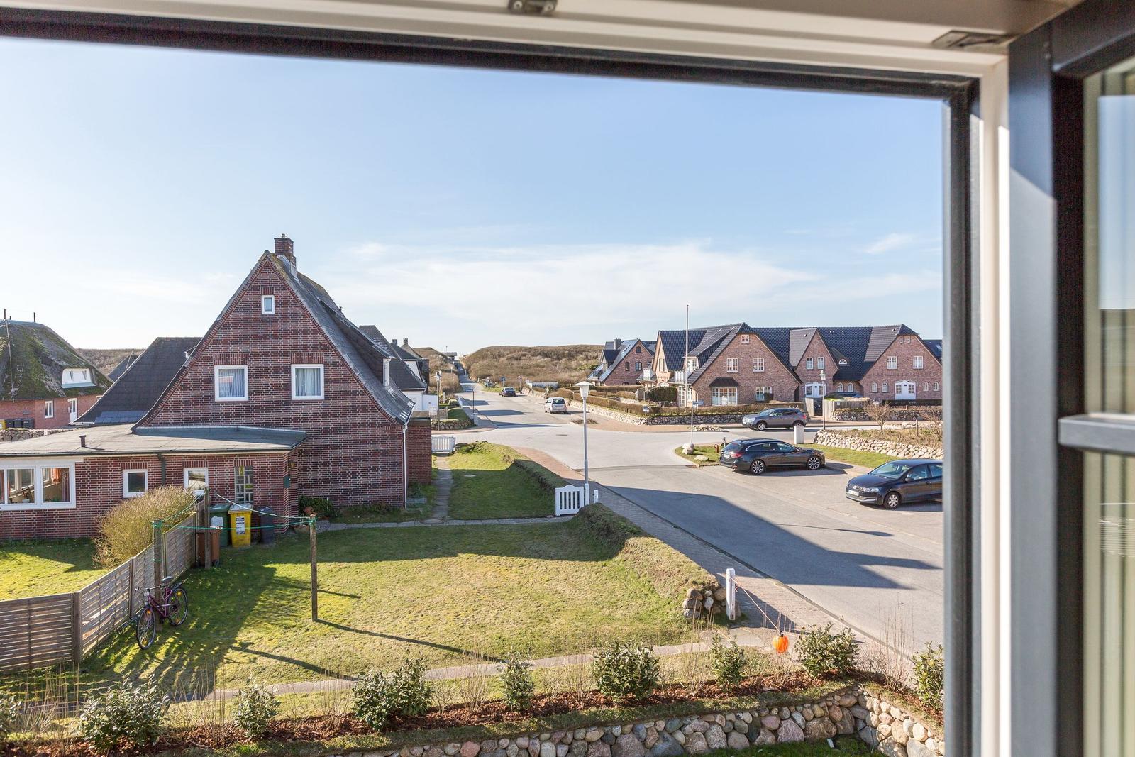 View through window onto street with houses and green areas