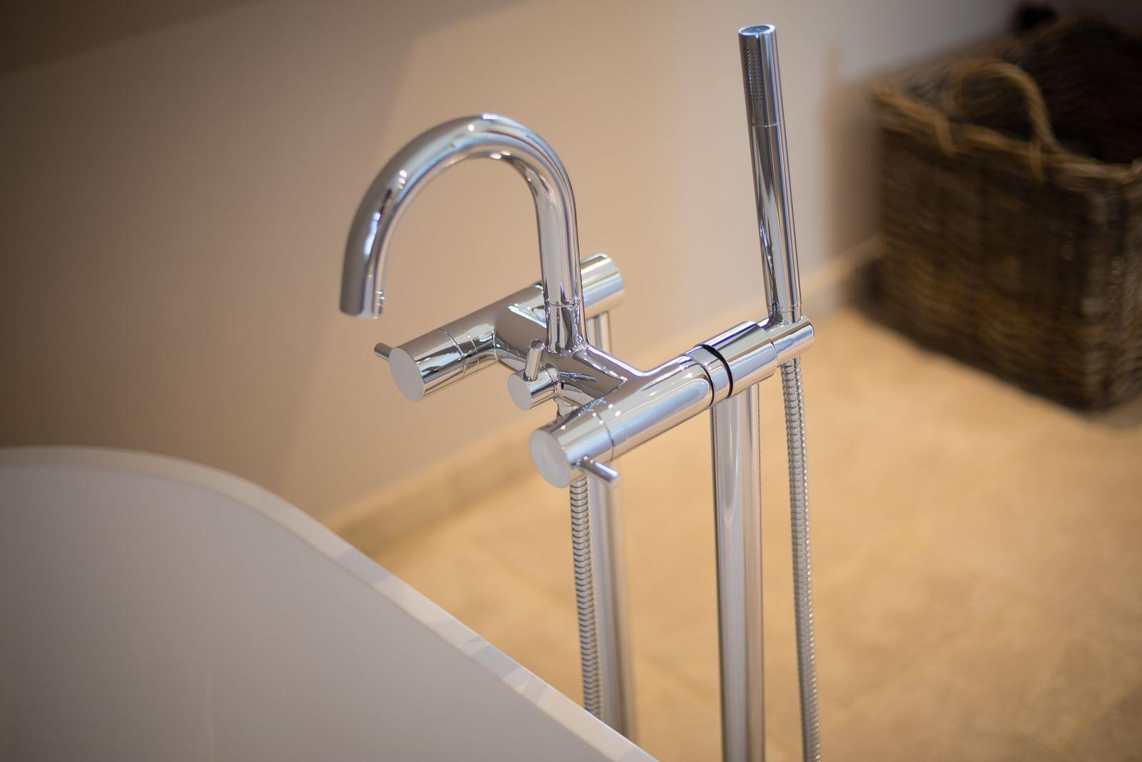 Shower head and faucet beside white bathtub rim