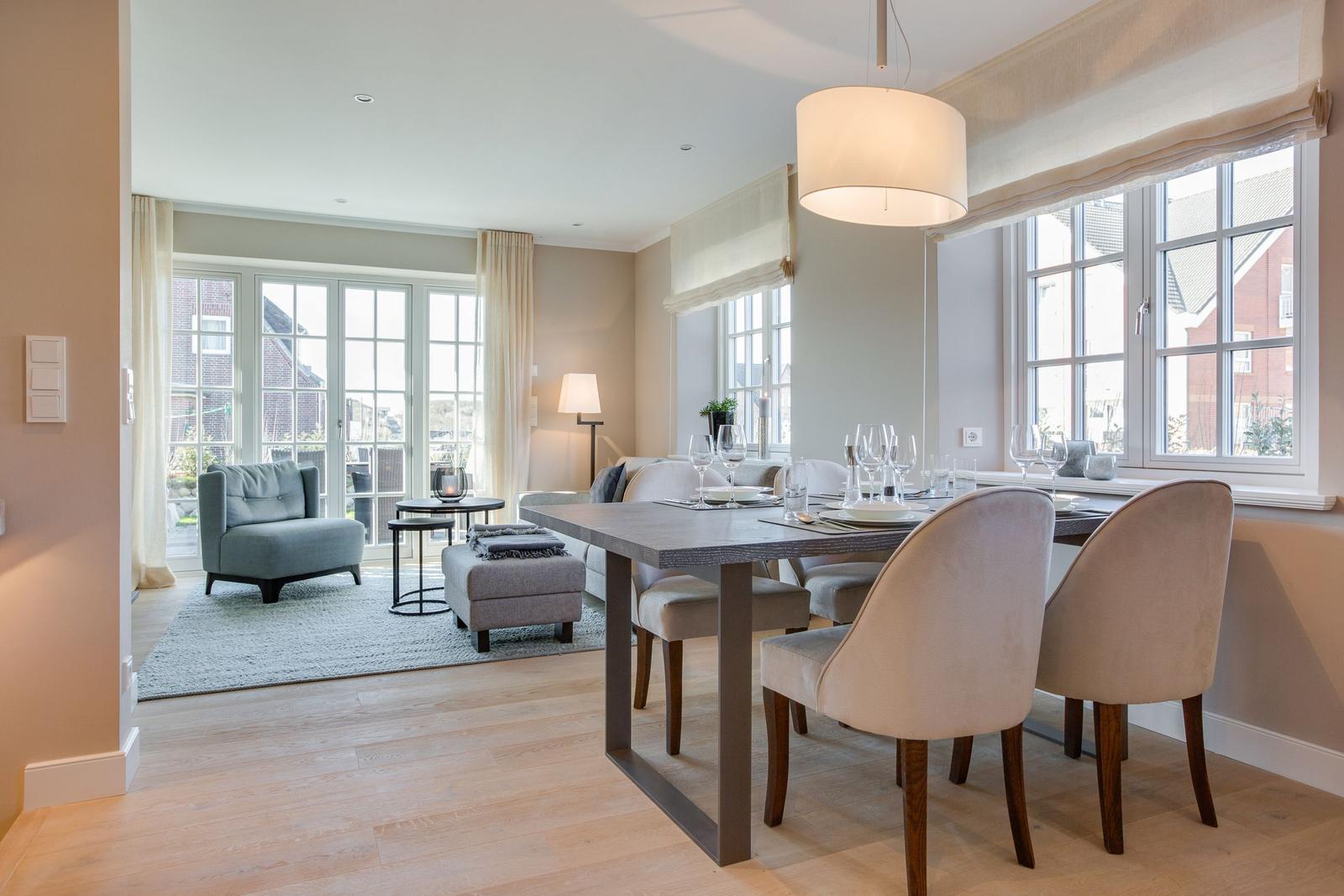 Dining room with table and chairs. Living area with armchair and windows.