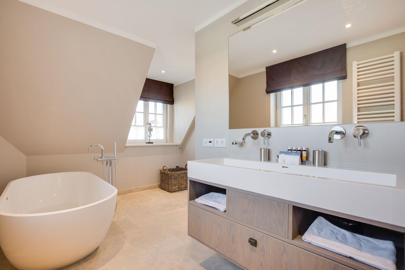 Bath with freestanding bathtub and sink with mirror.