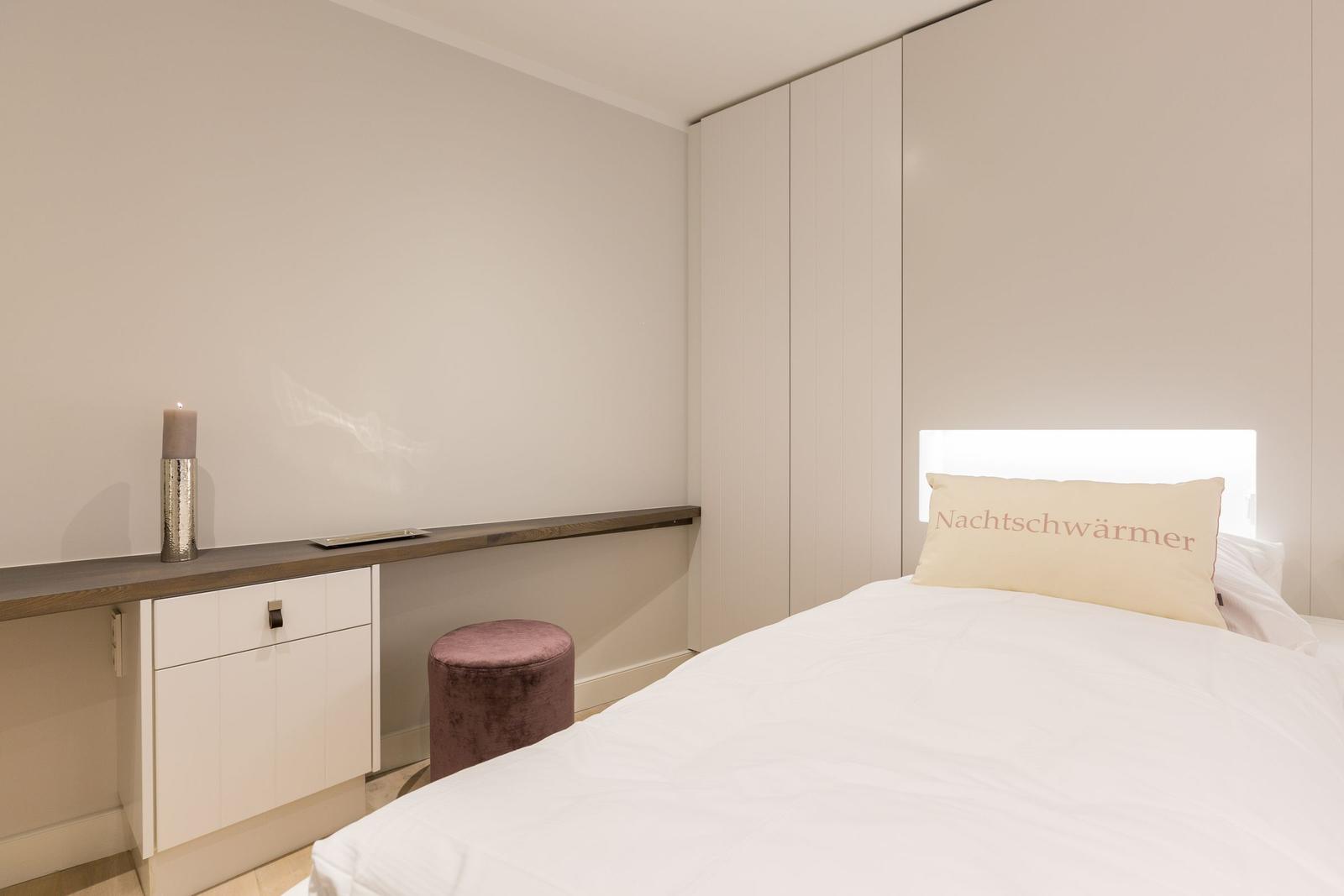 Bedroom with bed, nightstand, and wardrobe.