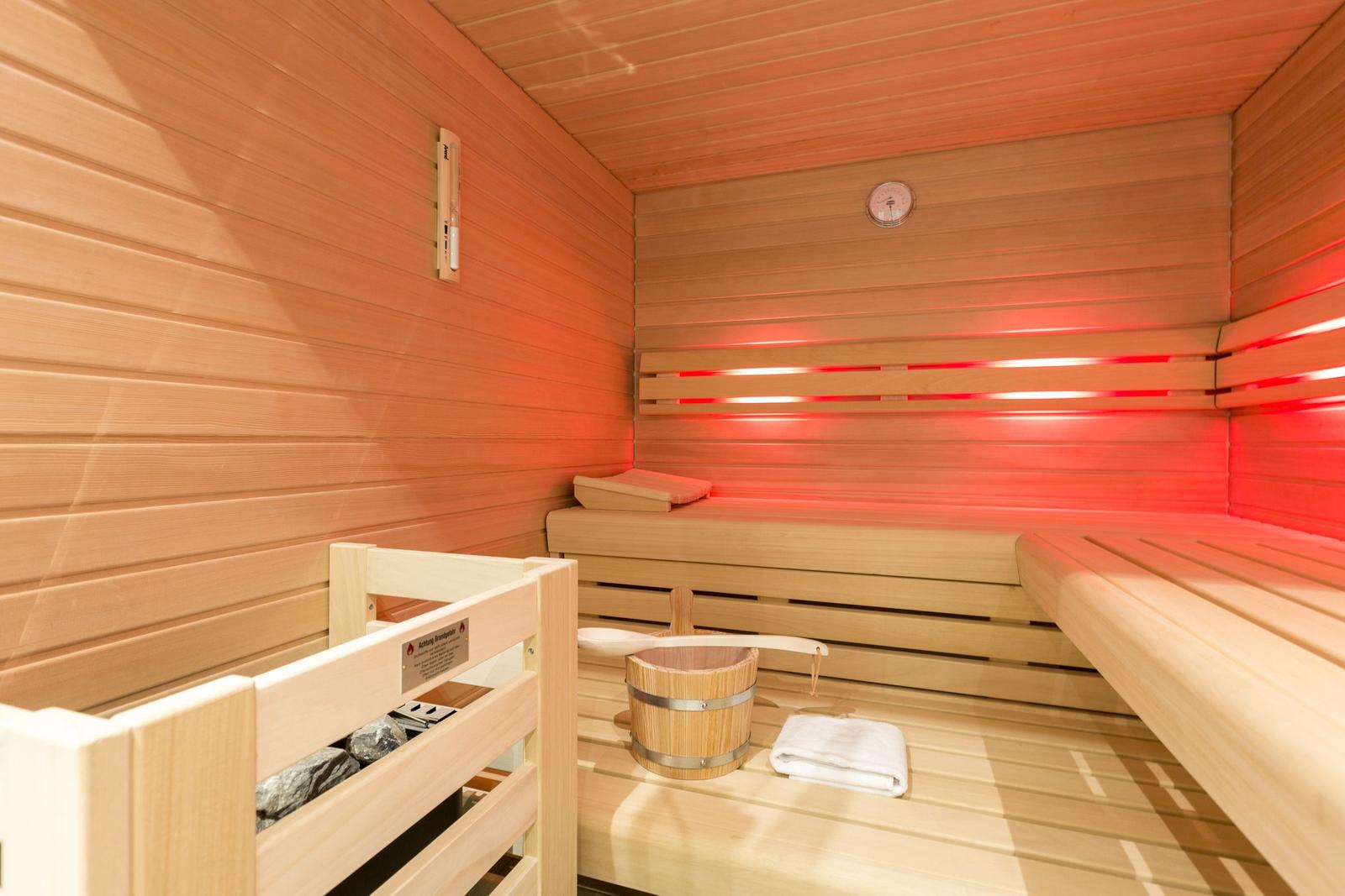 Sauna with wooden bench, bucket, and thermometer