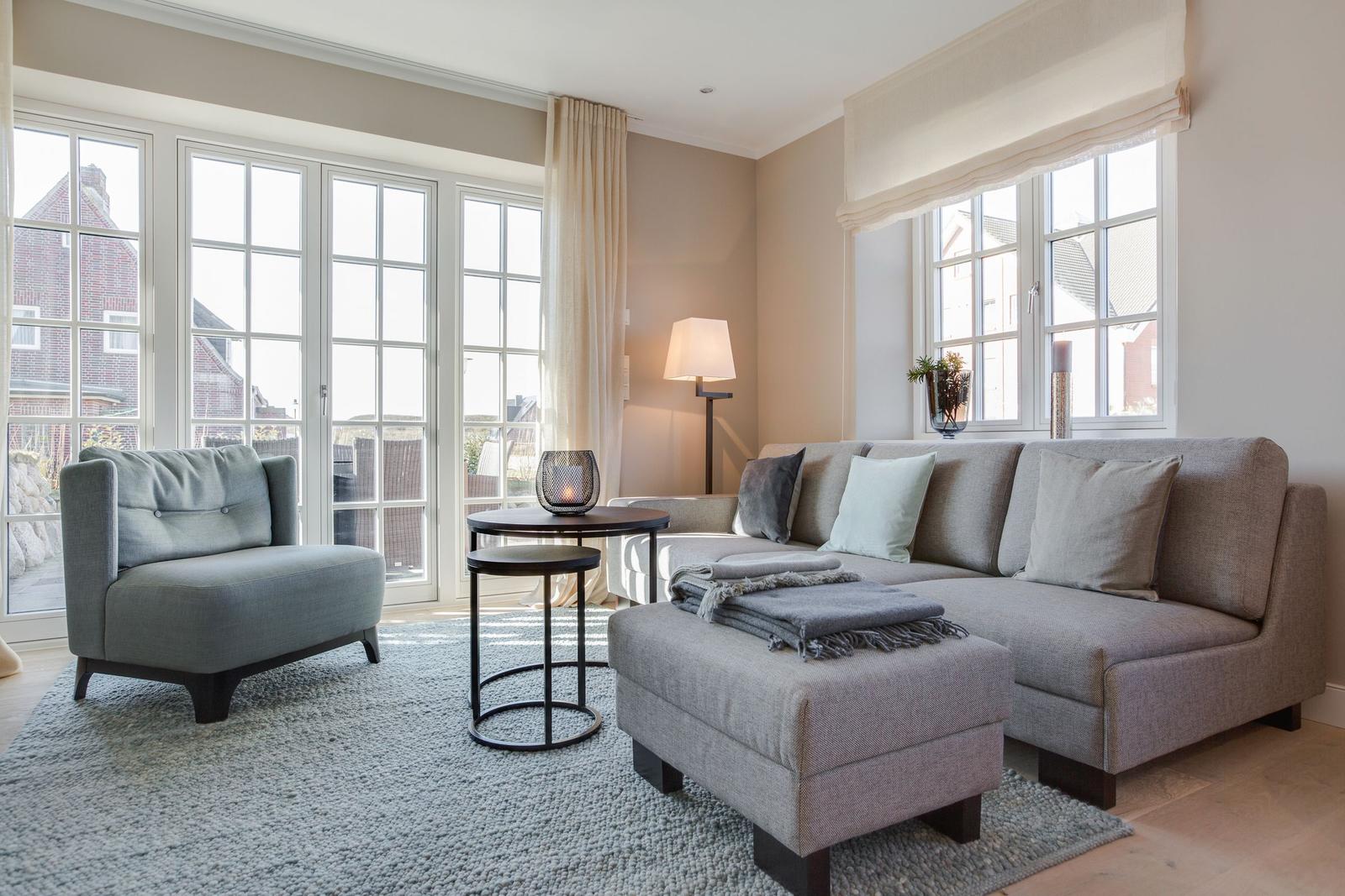 Living room with sofa, armchair, and large windows.