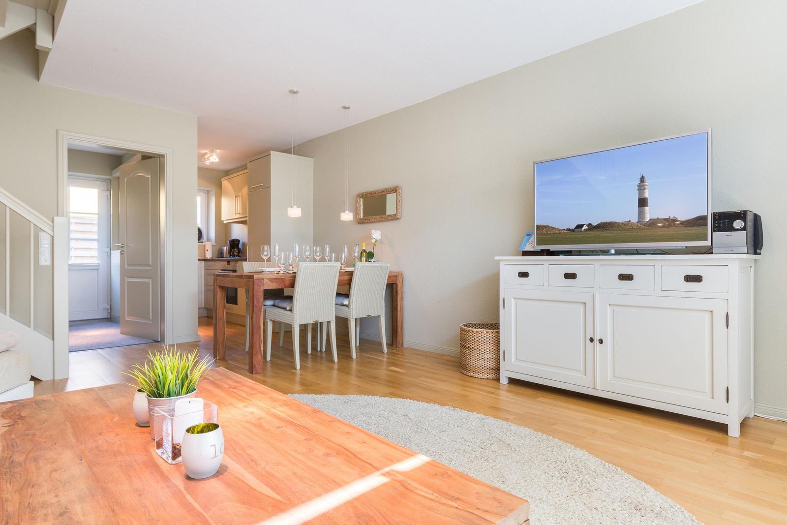 Living and dining area with hardwood floor, TV, and dining table with chairs.
