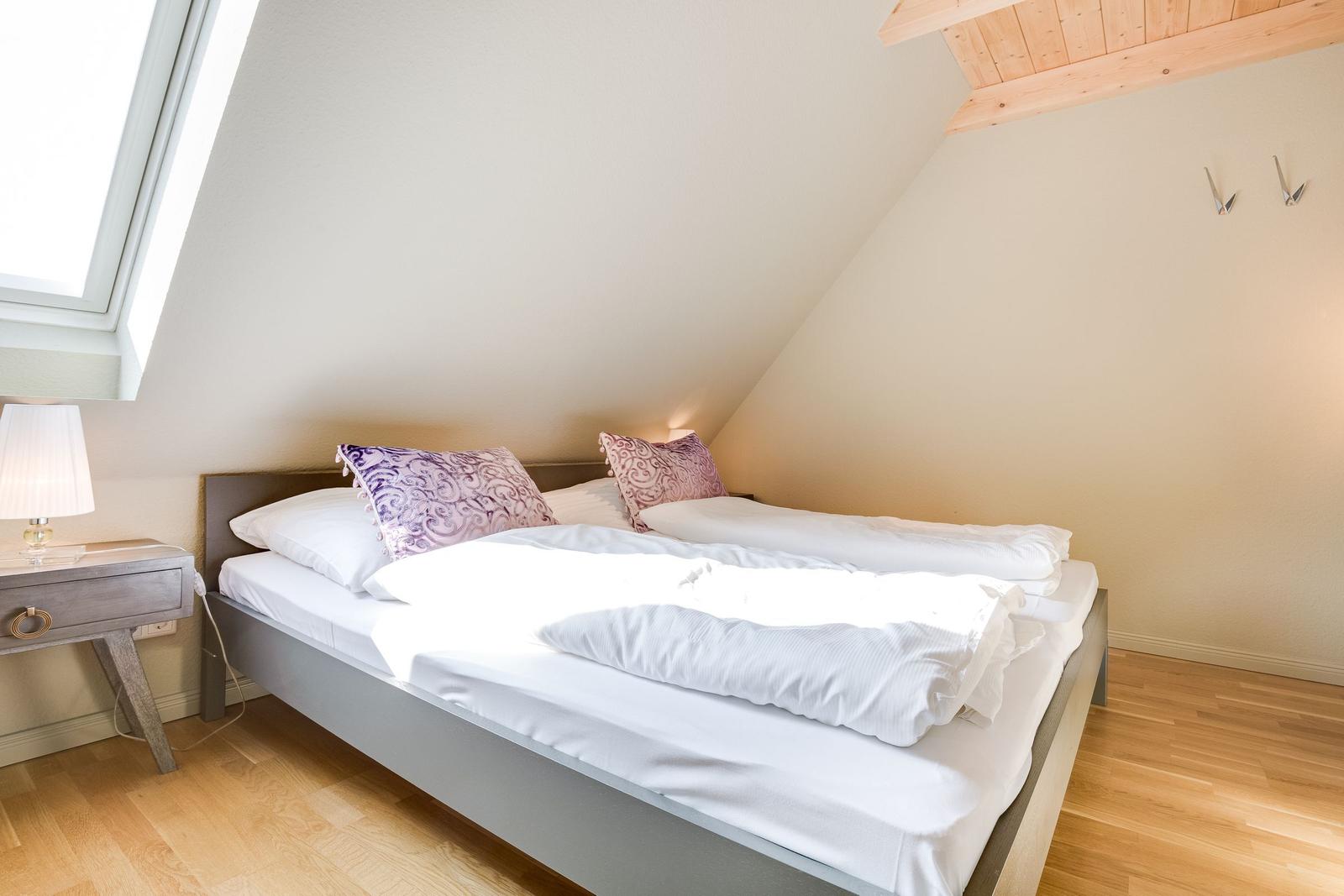 Bedroom with double bed, window, and wooden floor.