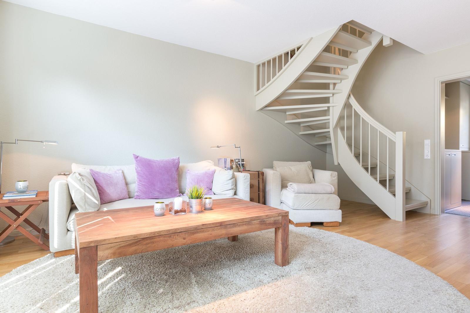 Living room with sofa, table, and spiral staircase.