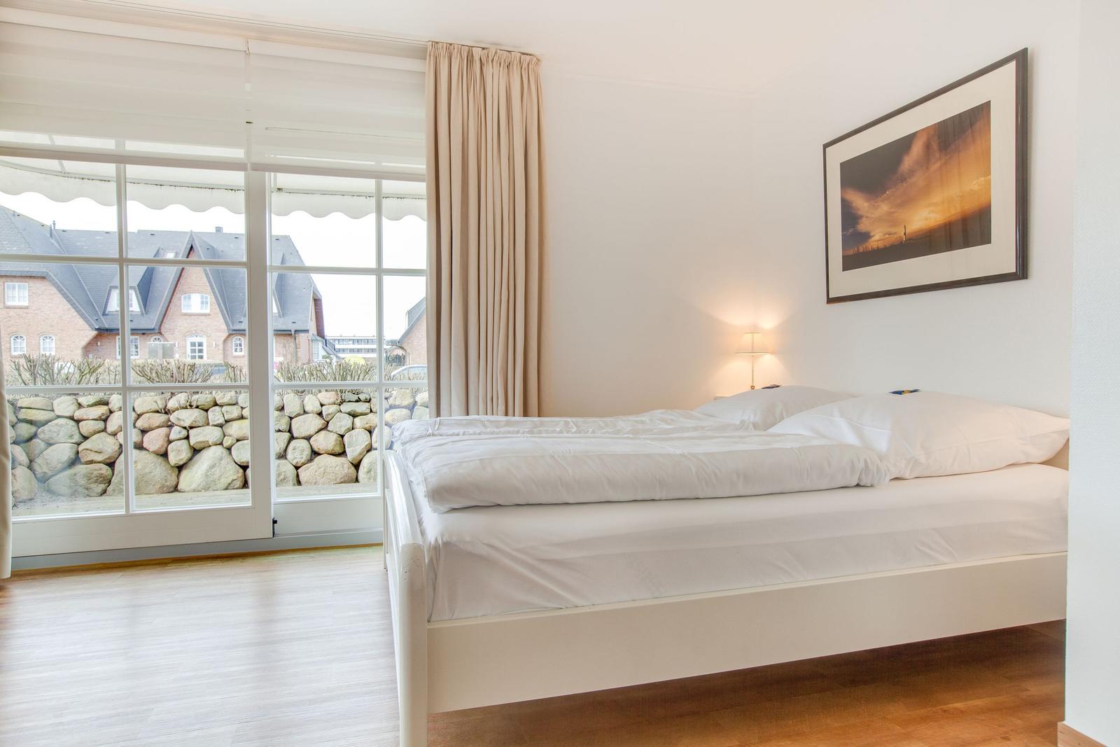 Bedroom with bed, window, and wall picture.