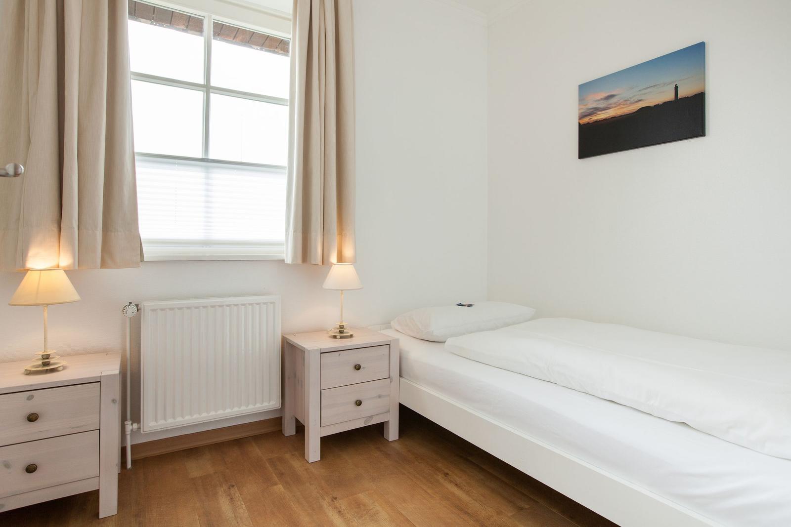 Bedroom with double bed, two nightstands, and window with curtains.