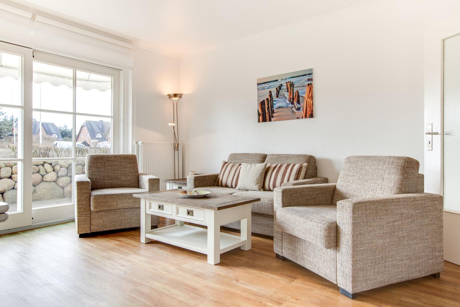 Living room with sofa, two armchairs, and table. Window with view outside.