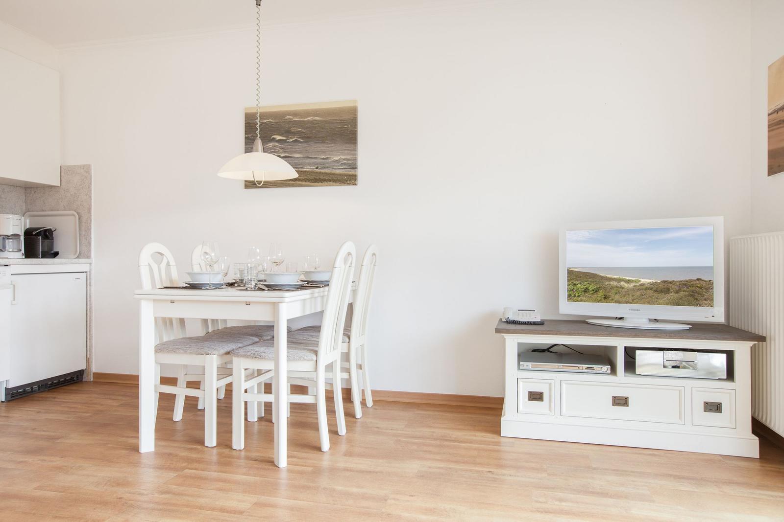 Dining area with table, chairs, and TV on media console.