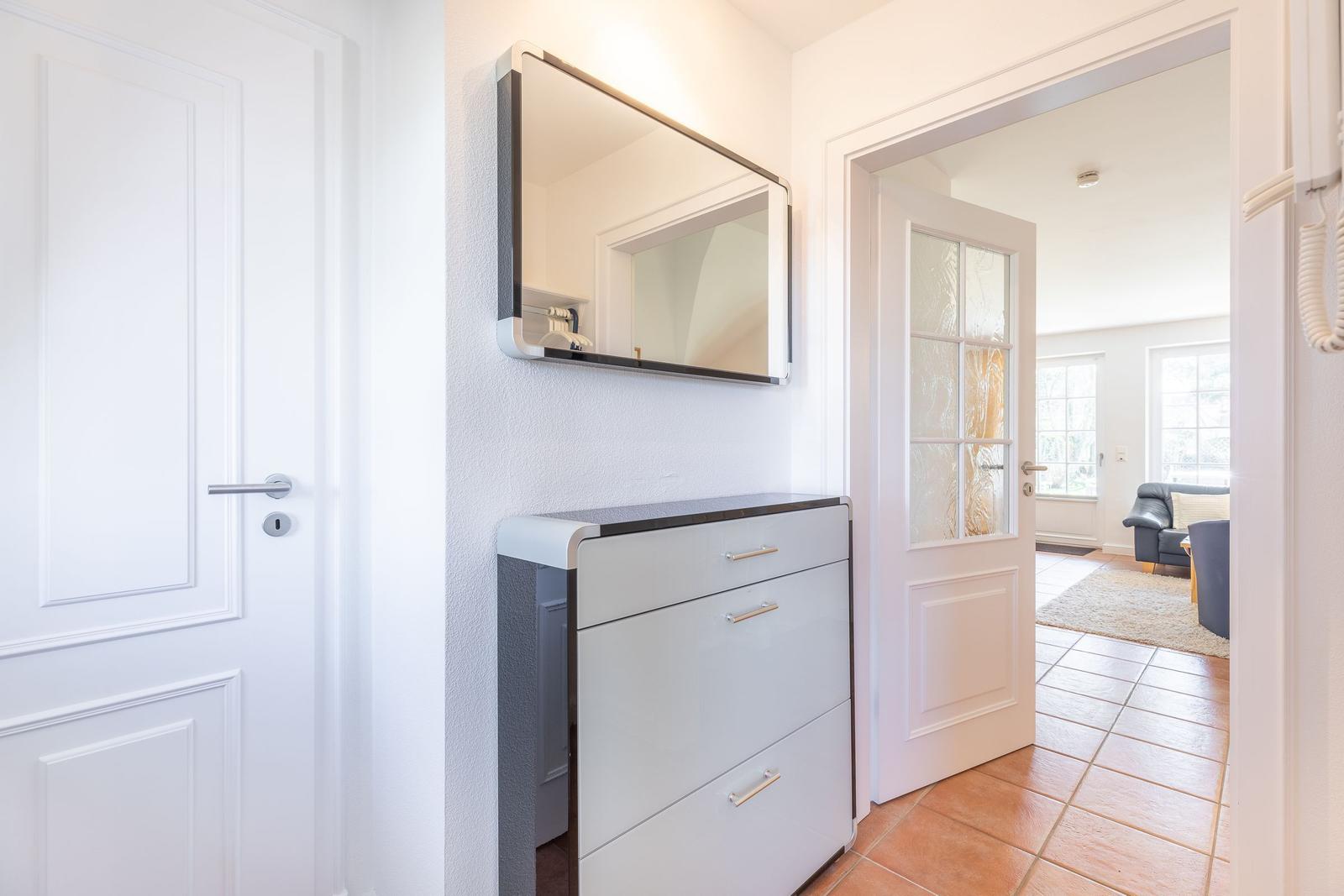 Hallway with shoe cabinet, mirror, and view into living room.