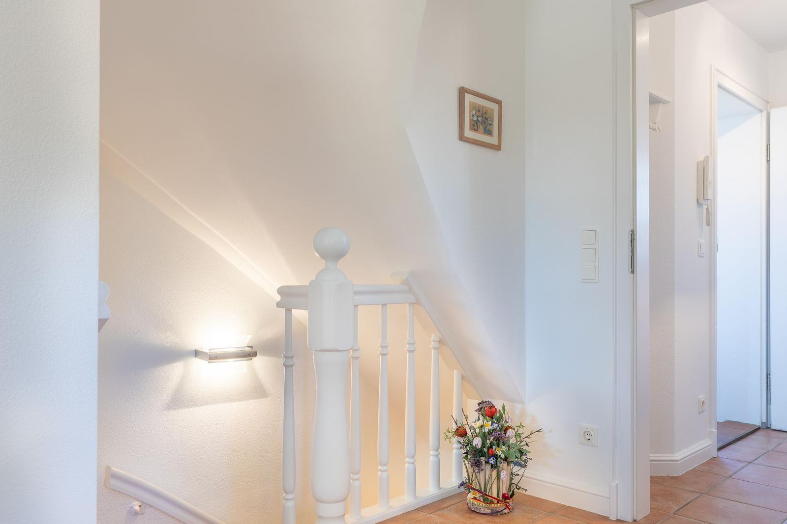 Staircase with white railings and flower basket on the floor.