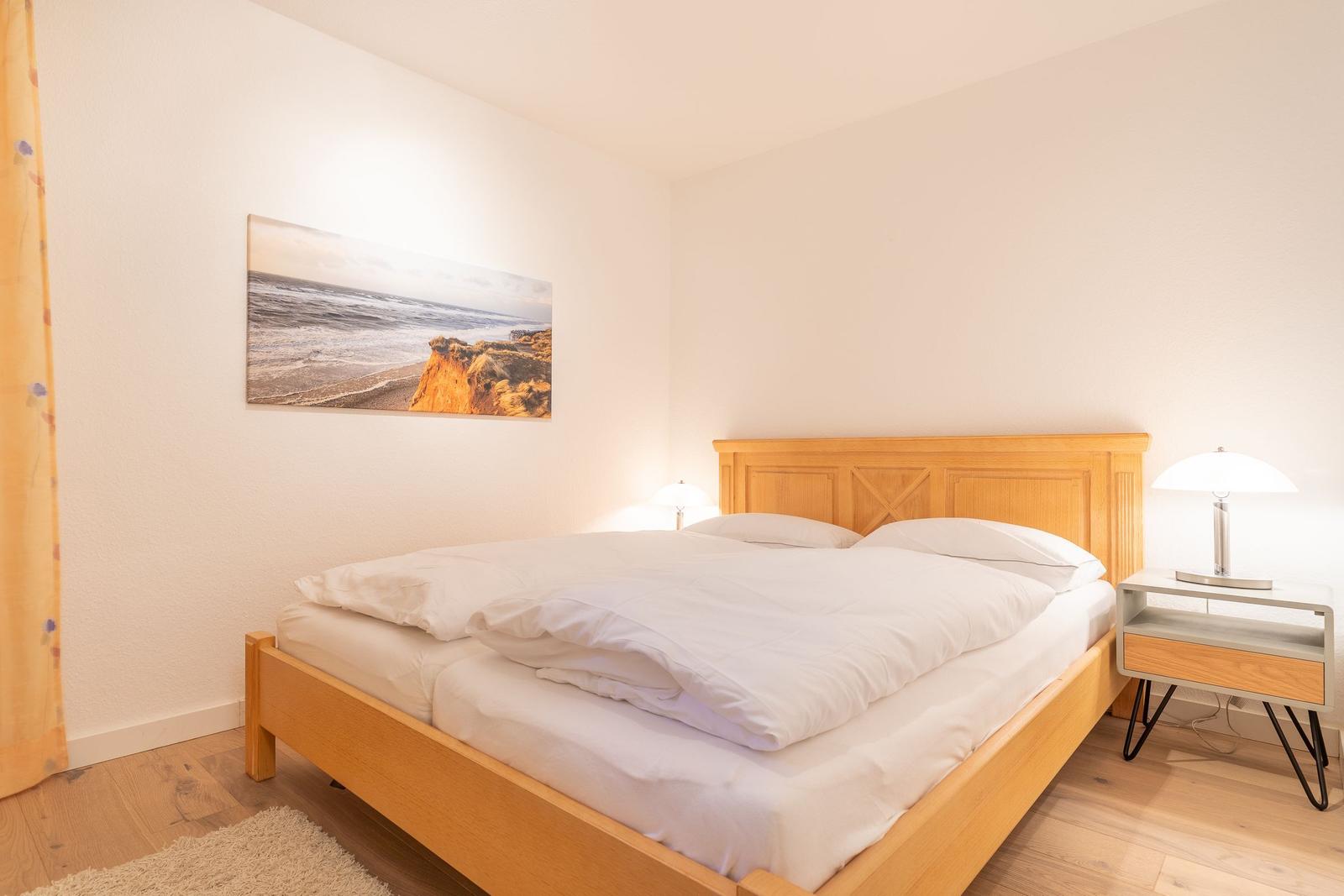 Bedroom with wooden bed, nightstand, and wall art on the wall.