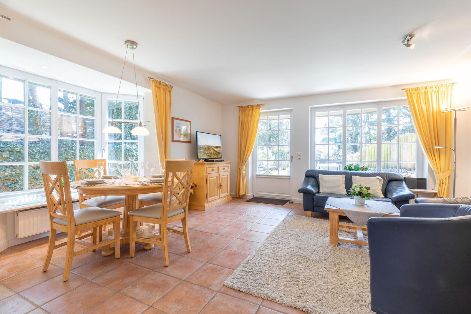 Living and dining area with wooden table, sofa, and large windows.