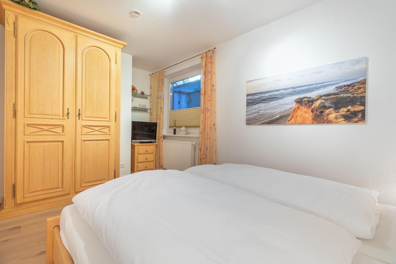 Bedroom with bed, wardrobe, and wall picture on the wall.