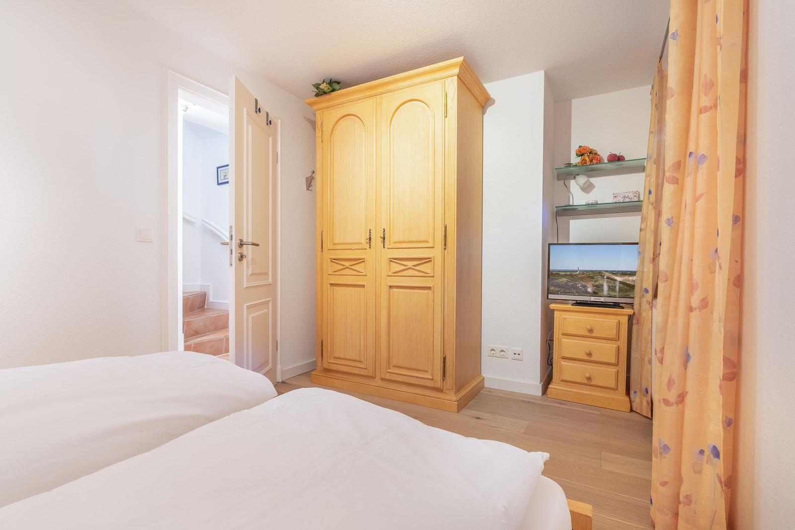 Room with two beds, wardrobe, and TV.