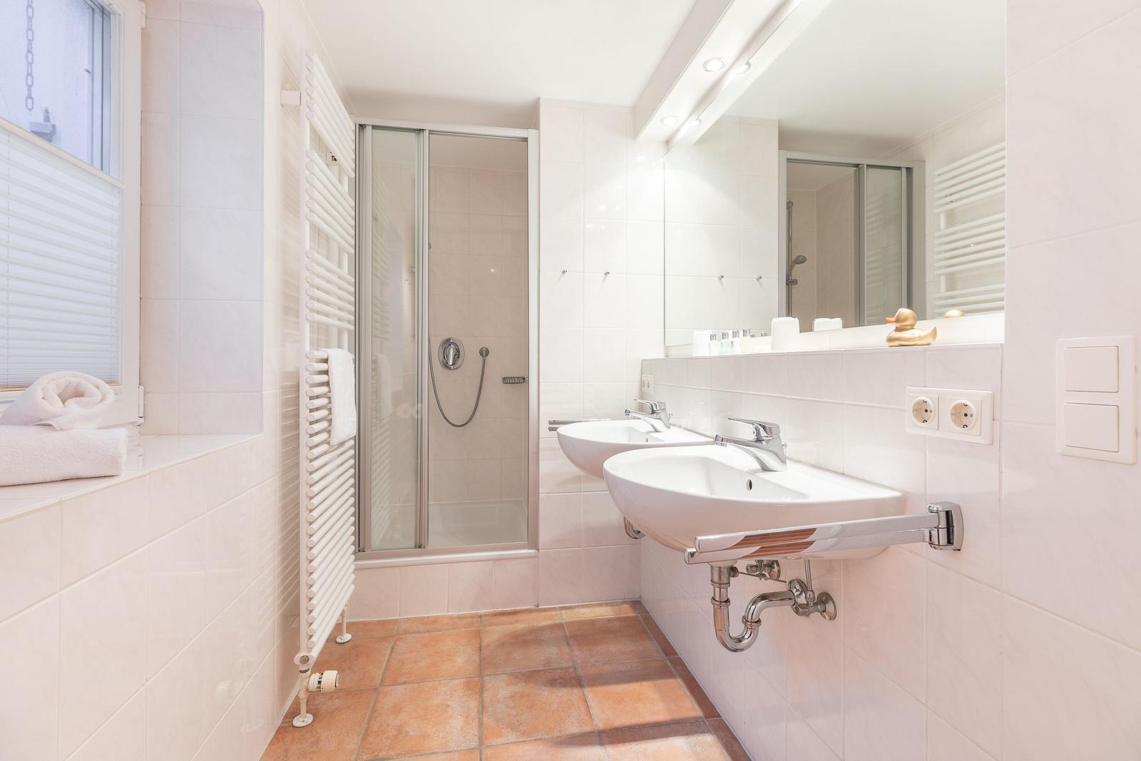 Bathroom with shower, two sinks, and window