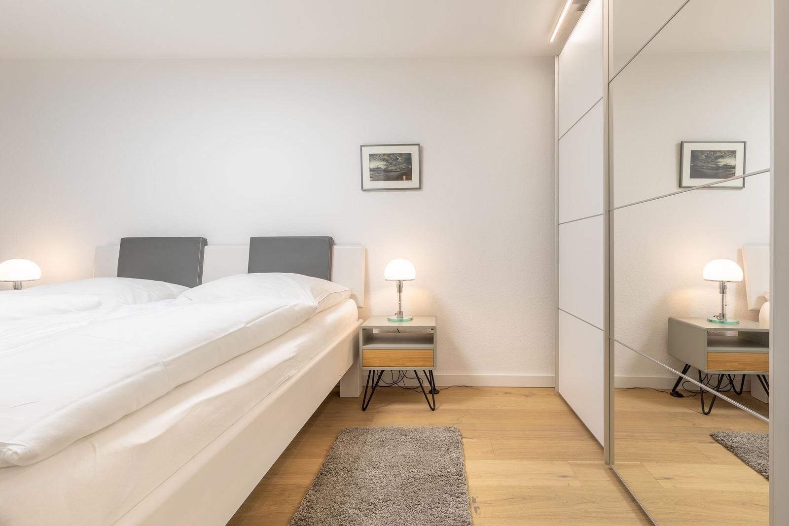 Bedroom with double bed, nightstand, and mirrored wardrobe.