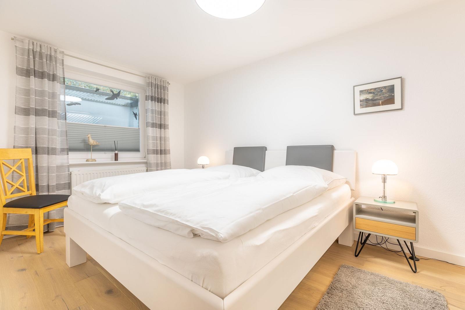 Bedroom with double bed, bedside table, and window with curtains.