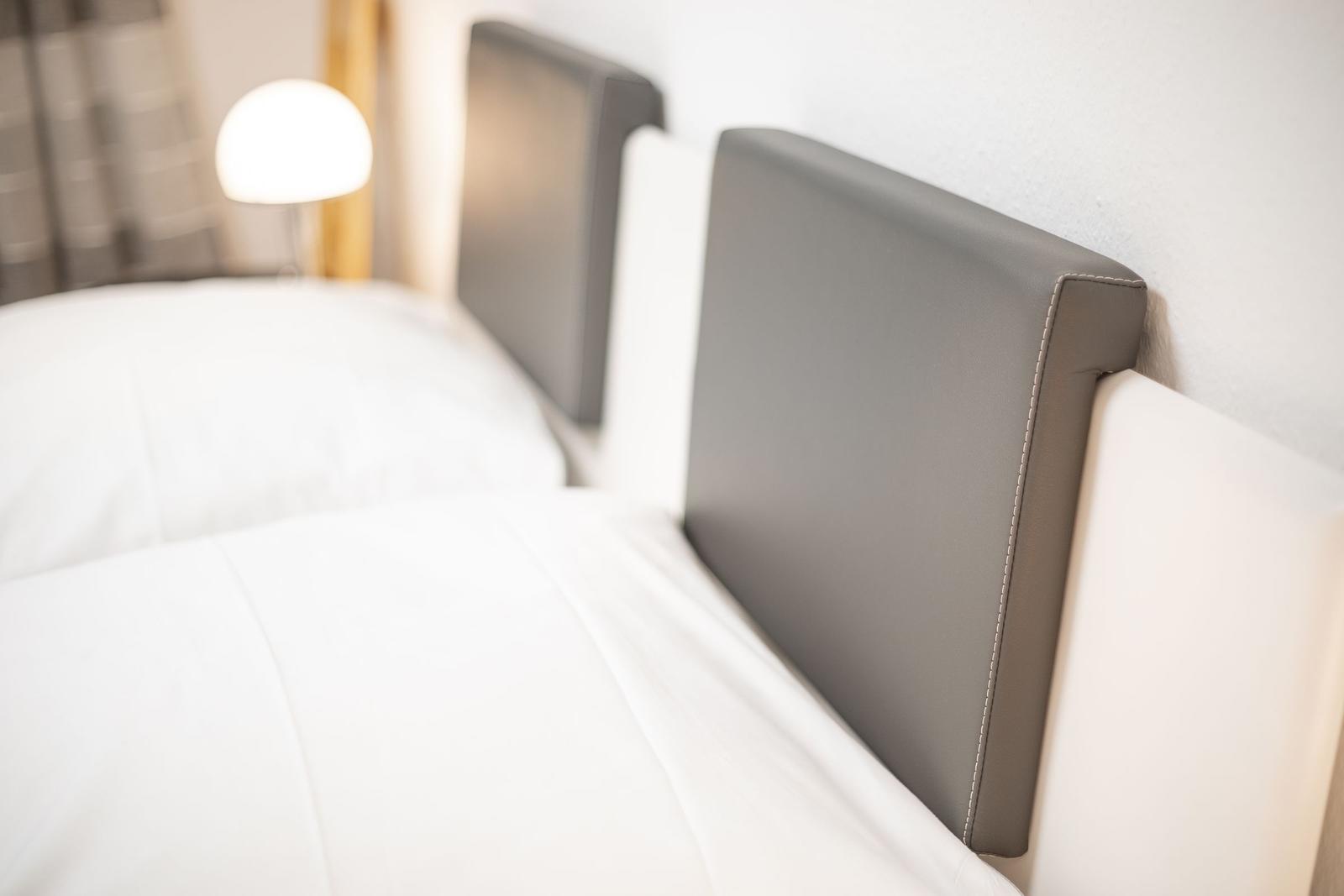Two beds with gray headboards and white bedding.