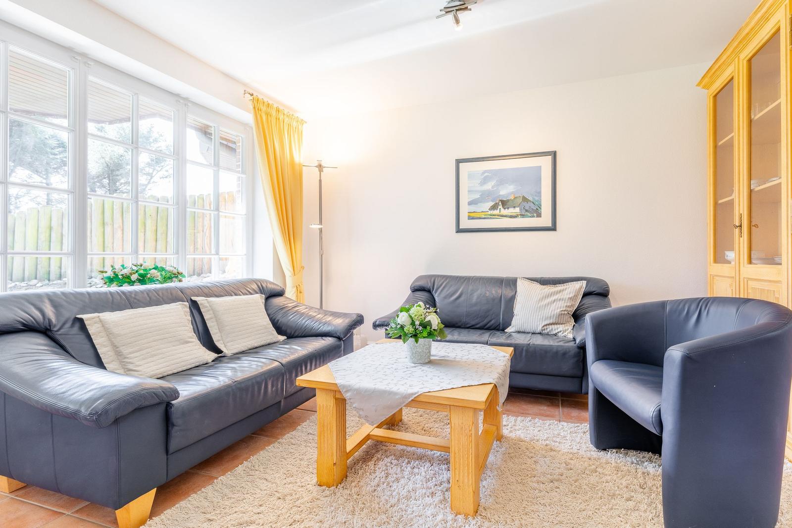 Living room with two sofas, armchair, table, and wall picture.