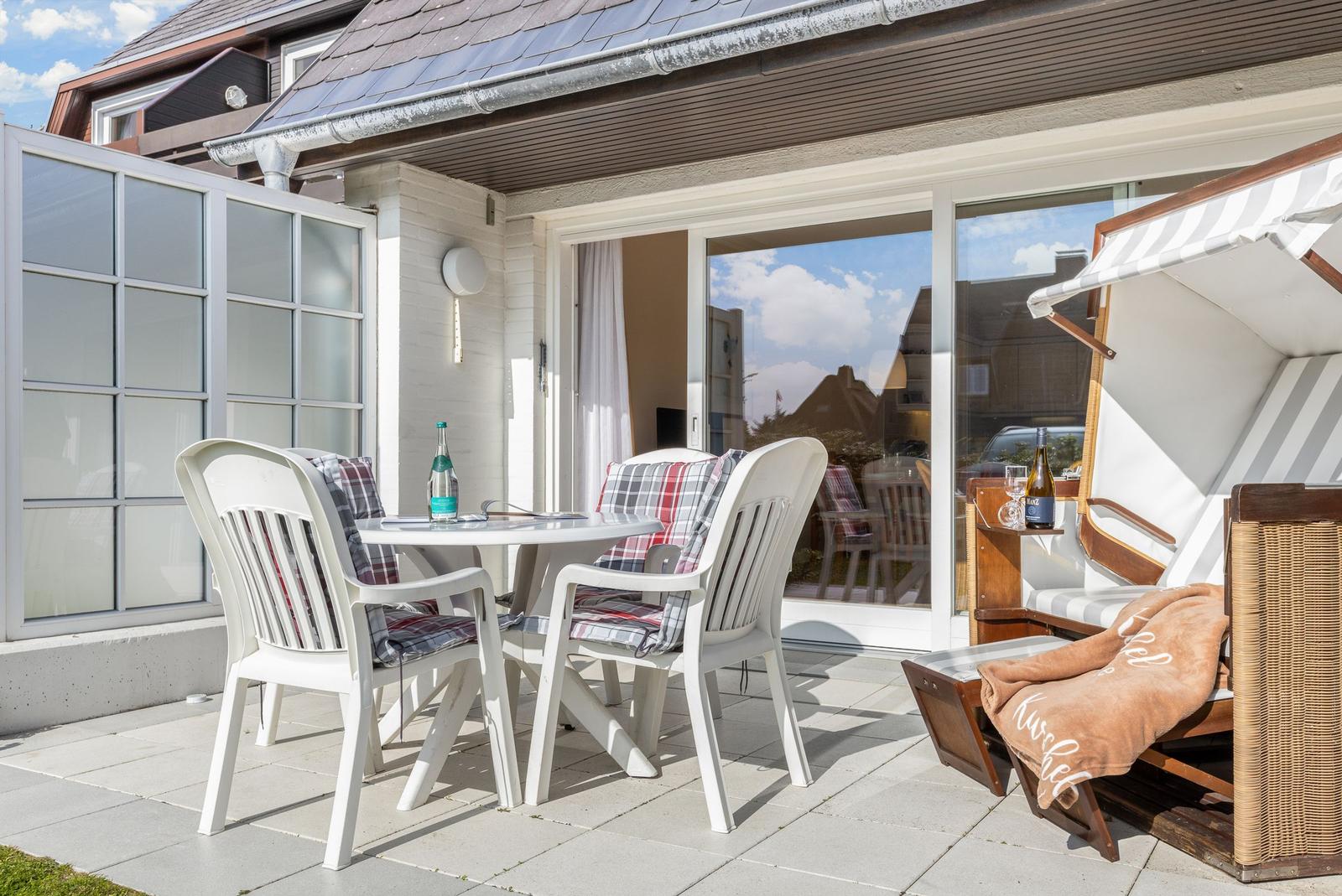 Terrace with table, chairs, and lounge under awning.