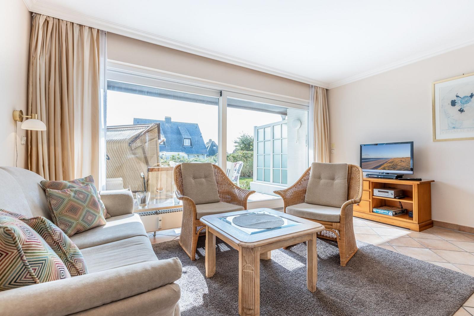 Living room with sofa, two chairs, and TV. Large window view to outdoor area.