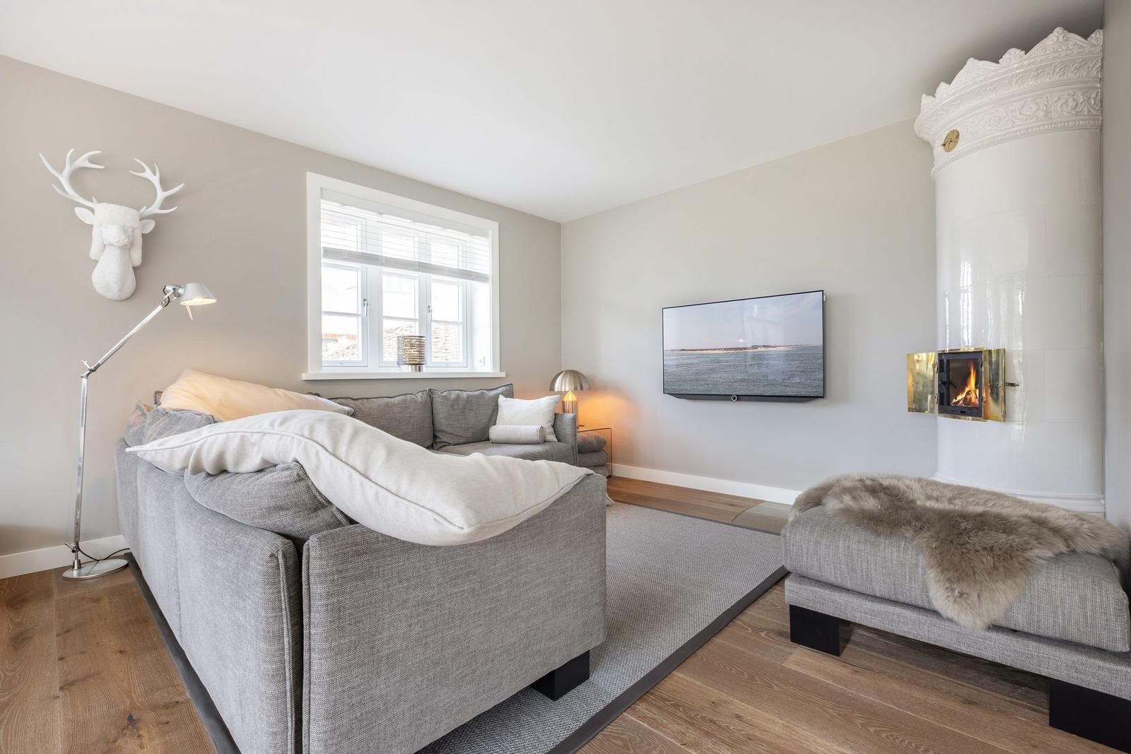 Wohnzimmer mit Sofa, Fernseher und Kamin