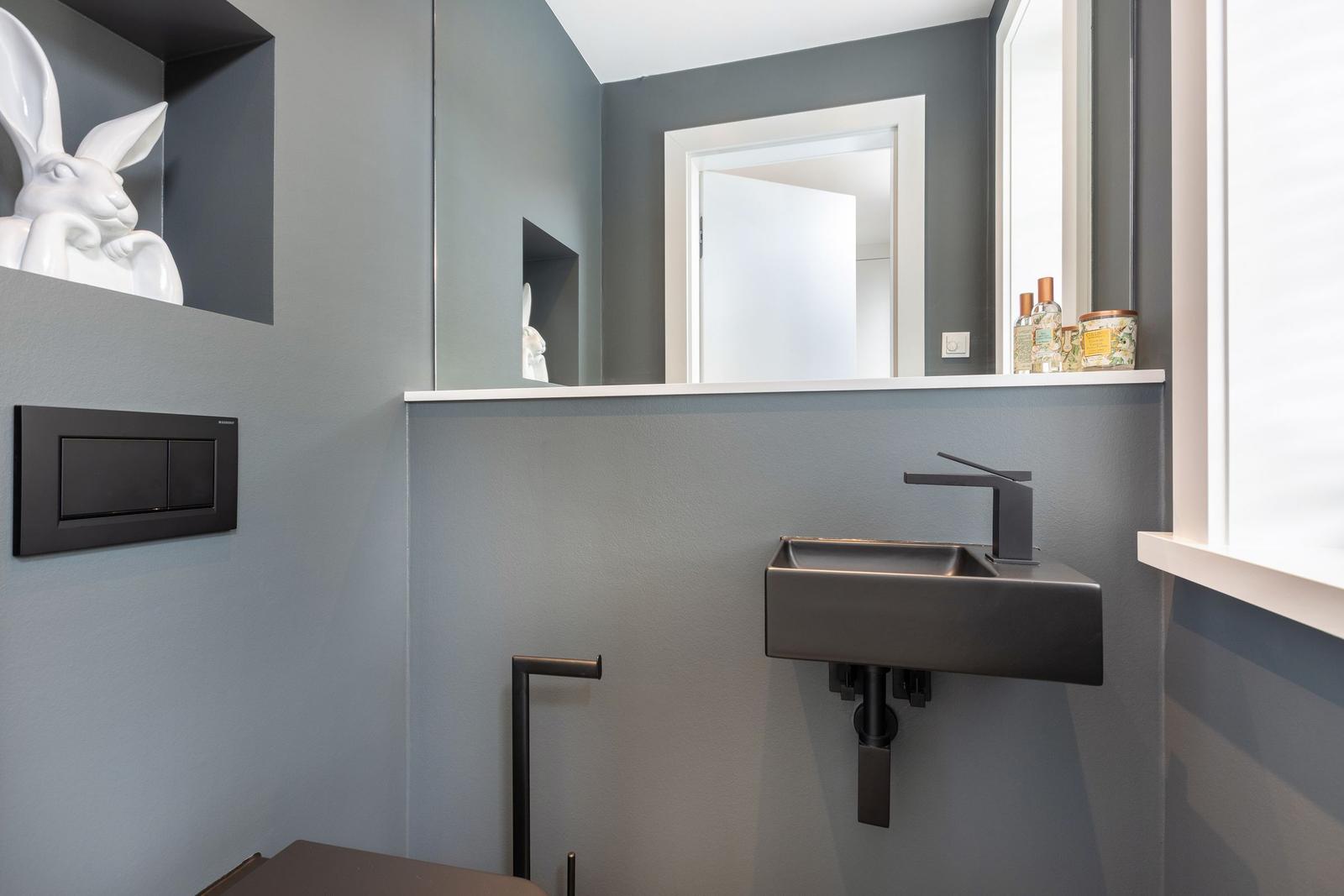 Badezimmer mit Waschbecken, Spiegel und Keramikfigur