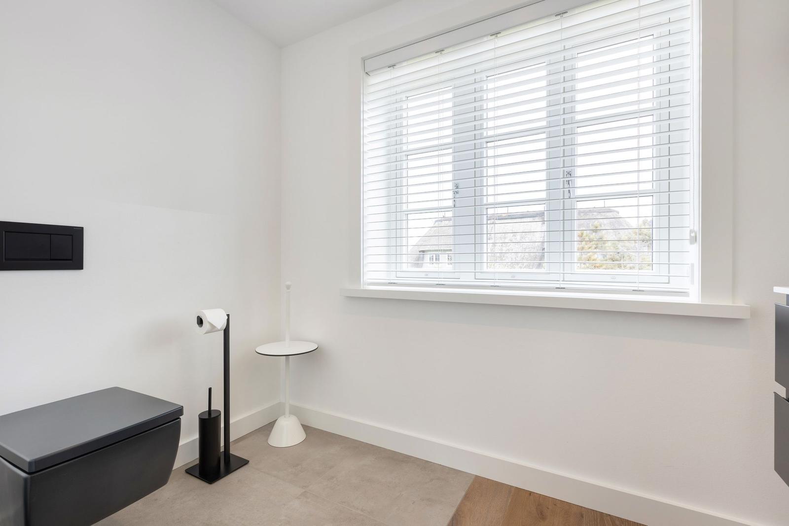 Sanitärzimmer mit Toilette, Fenster und Rollladen.
