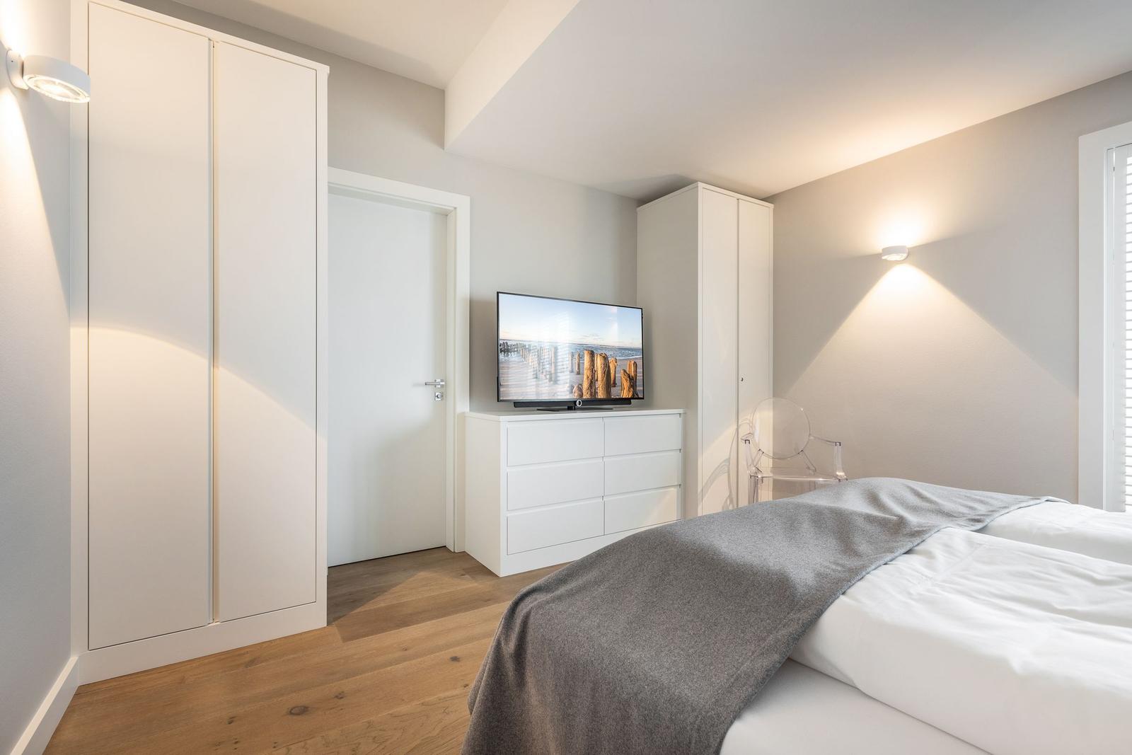Schlafzimmer mit Bett, TV und Kleiderschränken.