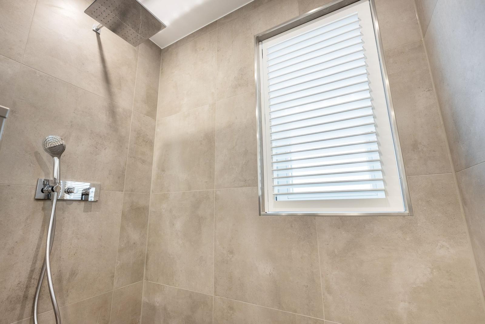Dusche mit Duschbrause und Fenster mit Jalousie