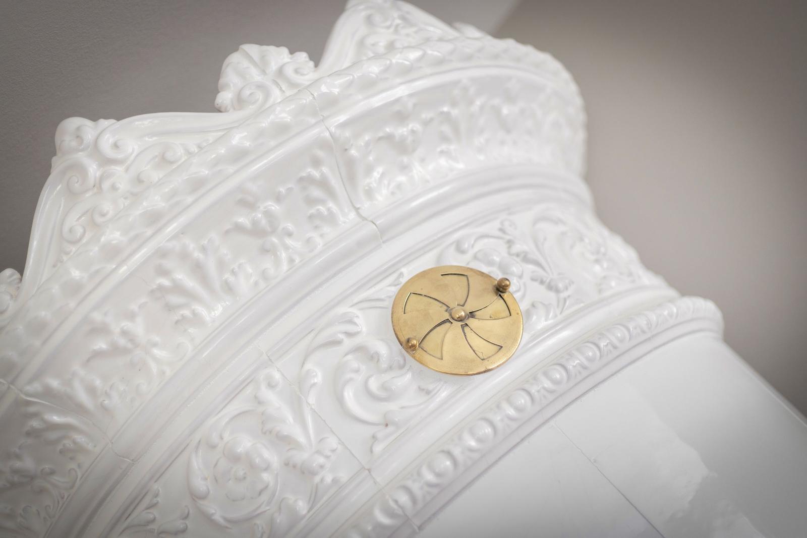 Weißer, verziertes Möbelstück mit goldenem Knopf.