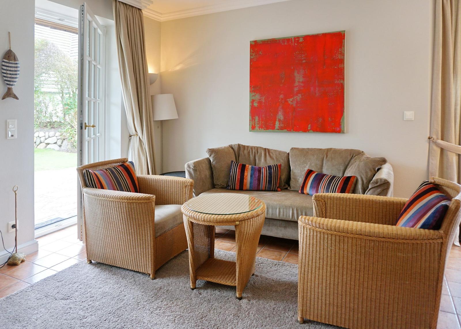 Wohnzimmer mit Sofa, zwei Sesseln und einem Tisch. An der Wand hängt ein rotes Bild.