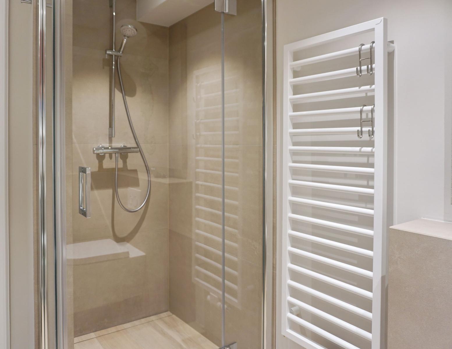 Dusche mit Glaswand und Heizkörper an der Wand