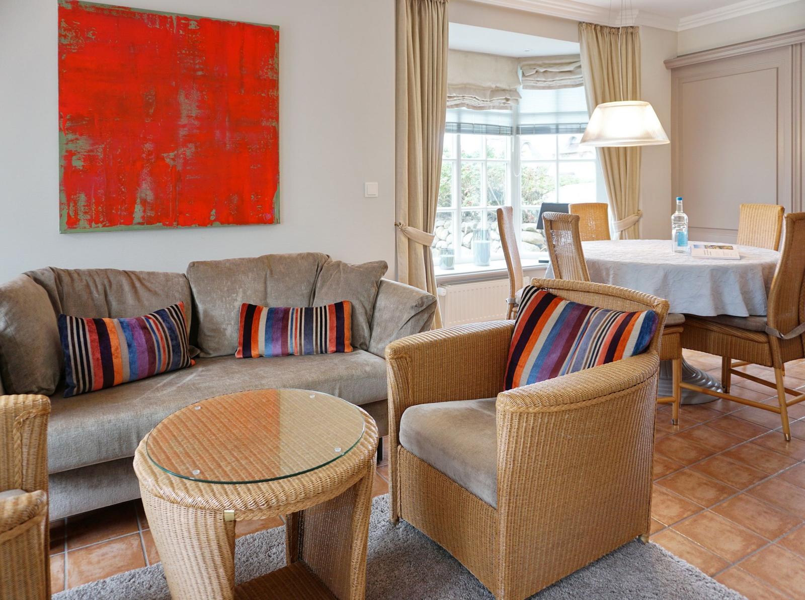 Wohnzimmer mit Sofa, Sessel und Esstisch. Große Fenster und rotes Wandbild.
