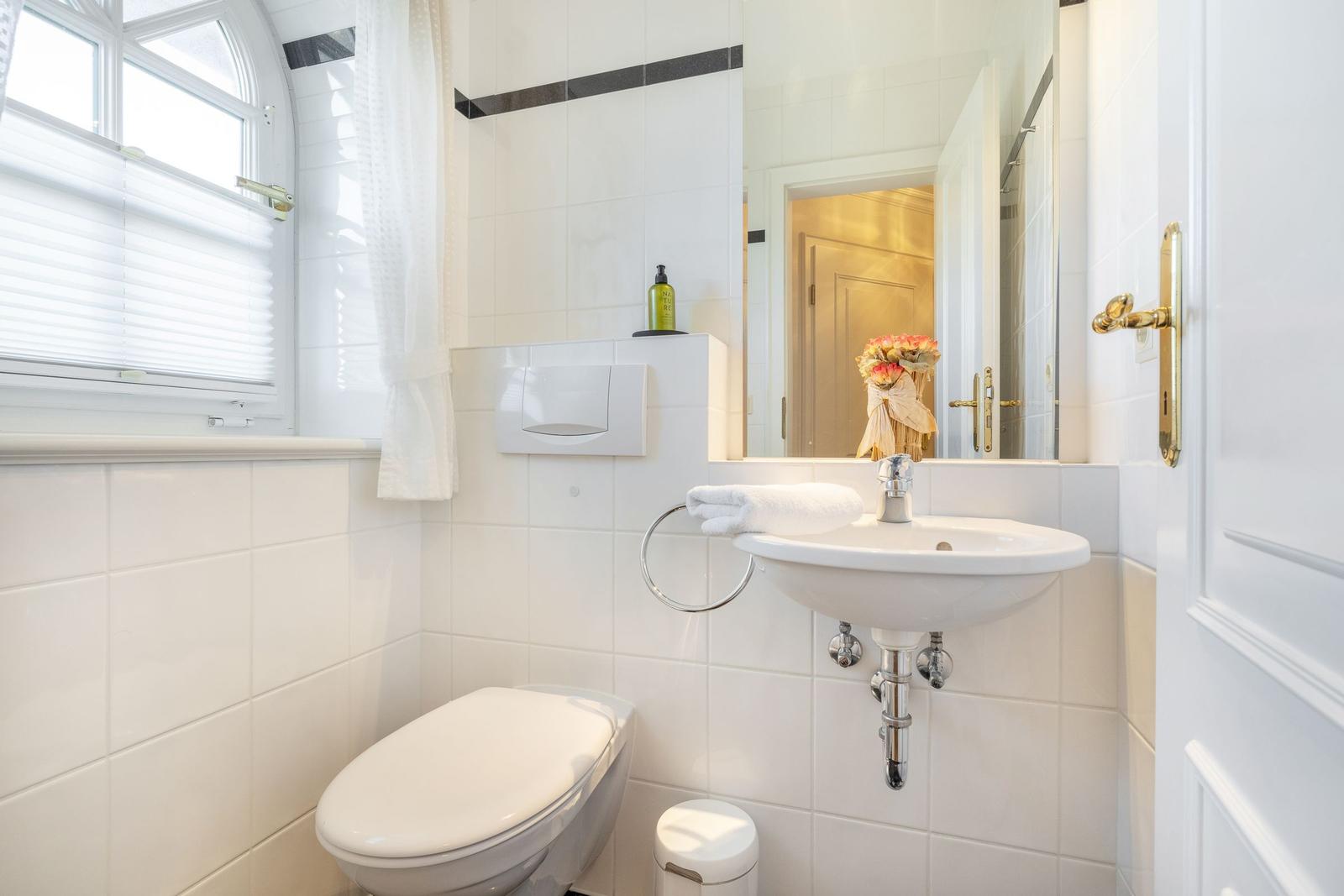 Bathroom with toilet, sink, and window.