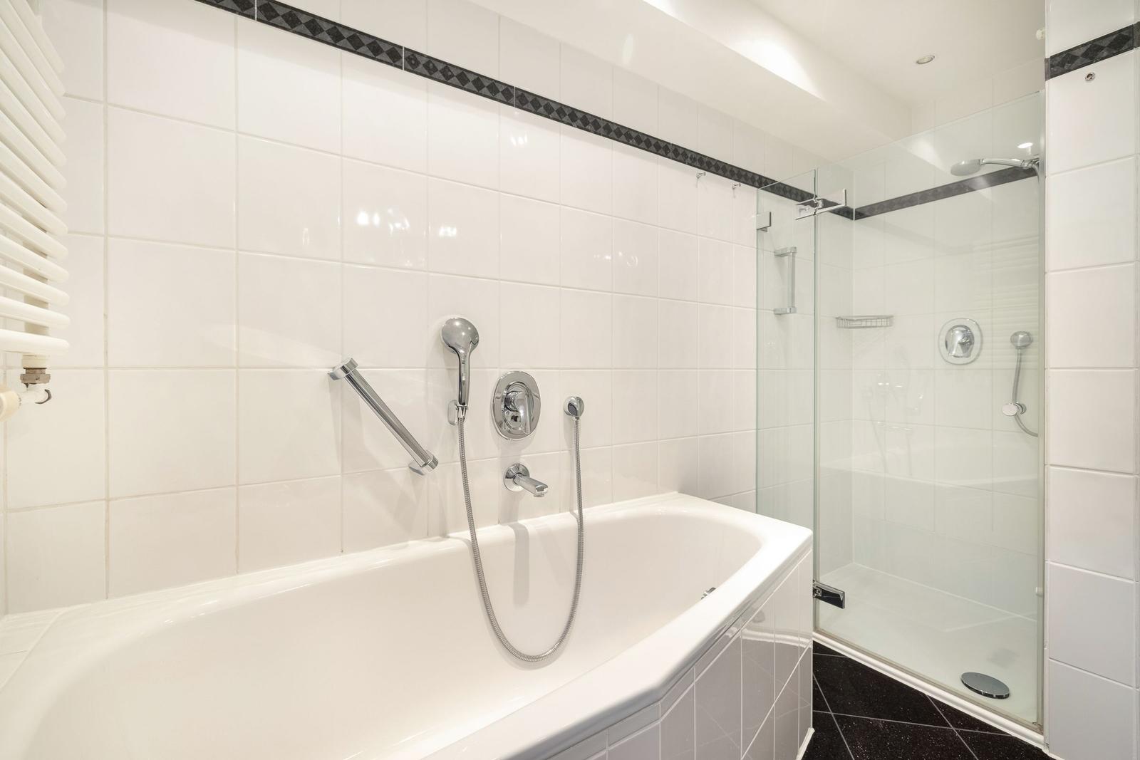 Bath with bathtub and shower, white tiles, black floor tiles