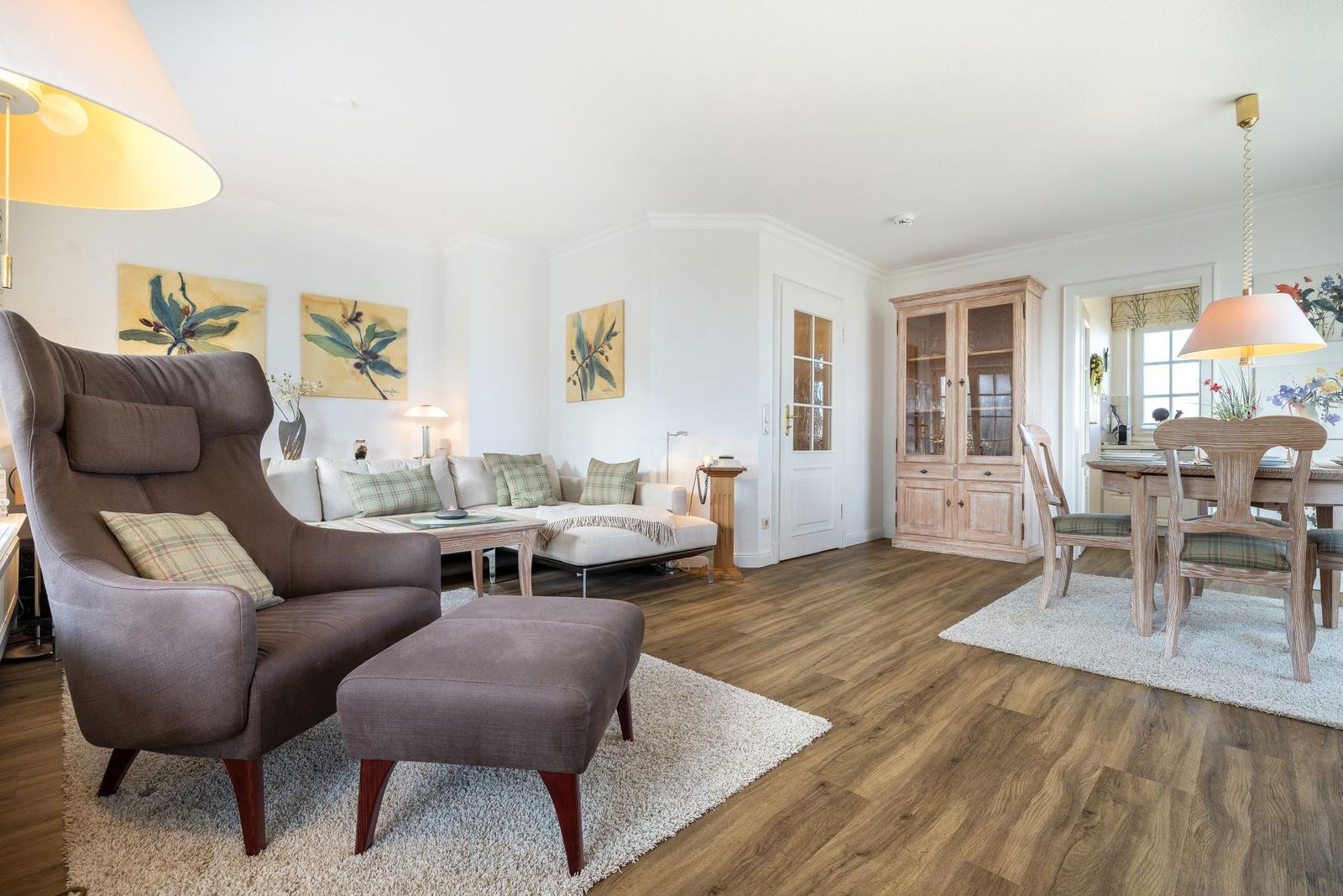 Living and dining area with seating, hardwood floor, and glass-front cabinet.