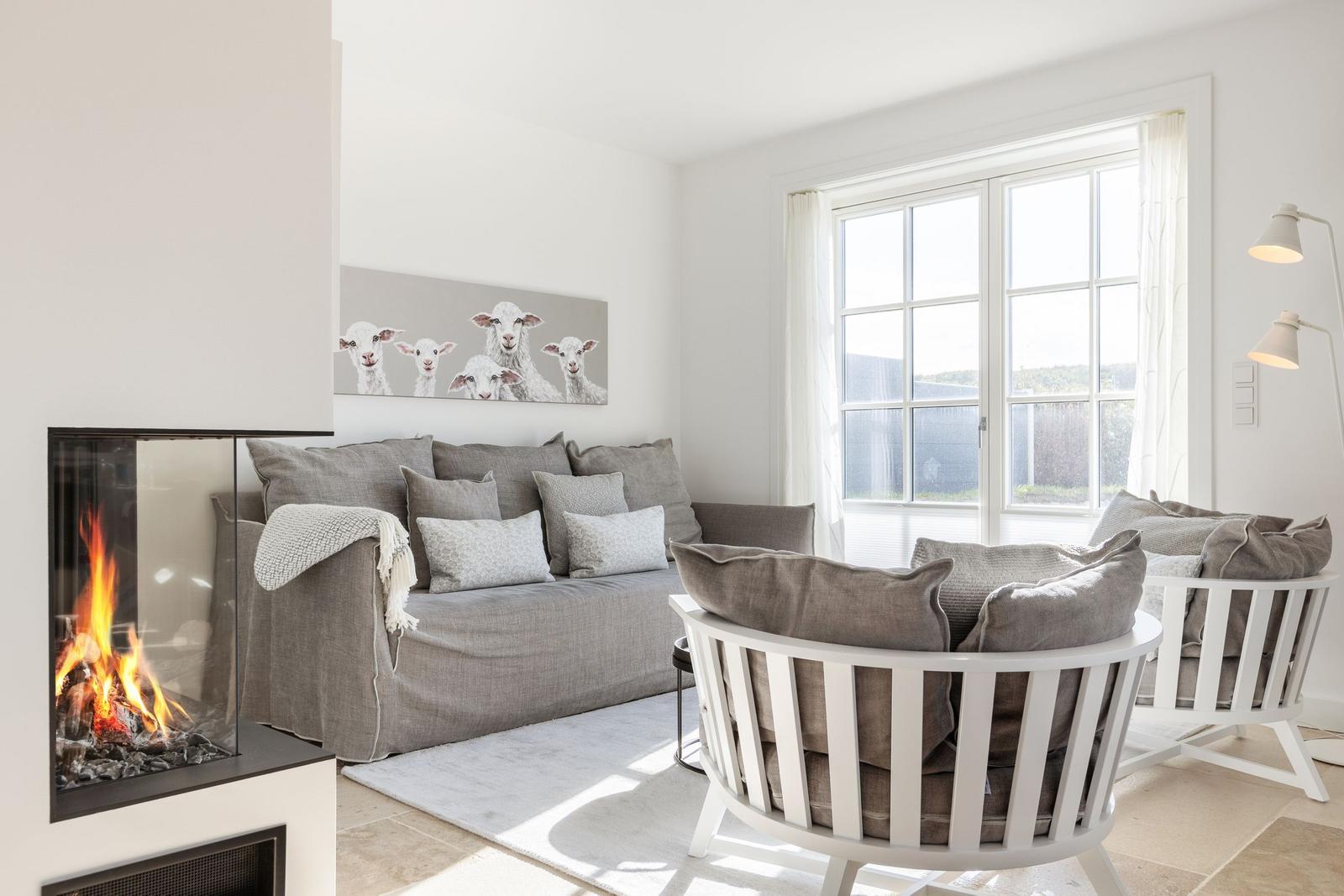 Living room with fireplace, sofa, and round chair. Window with view of outdoor area.