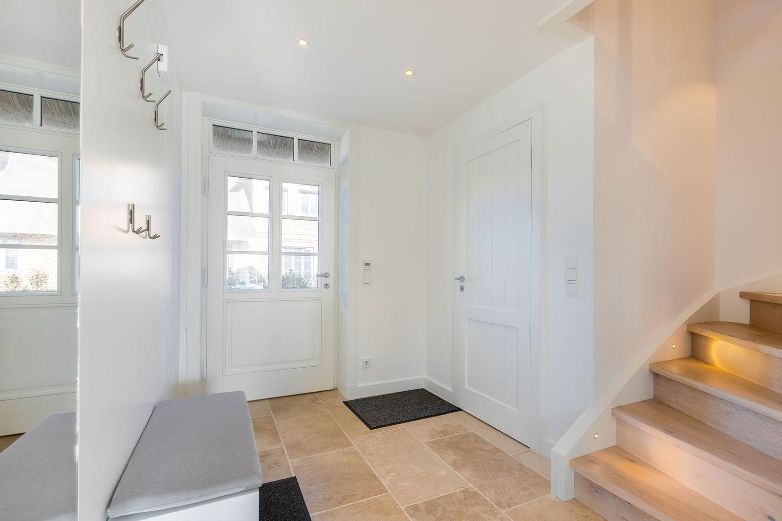 Entrance with wooden stairs, white doors, and stone floor