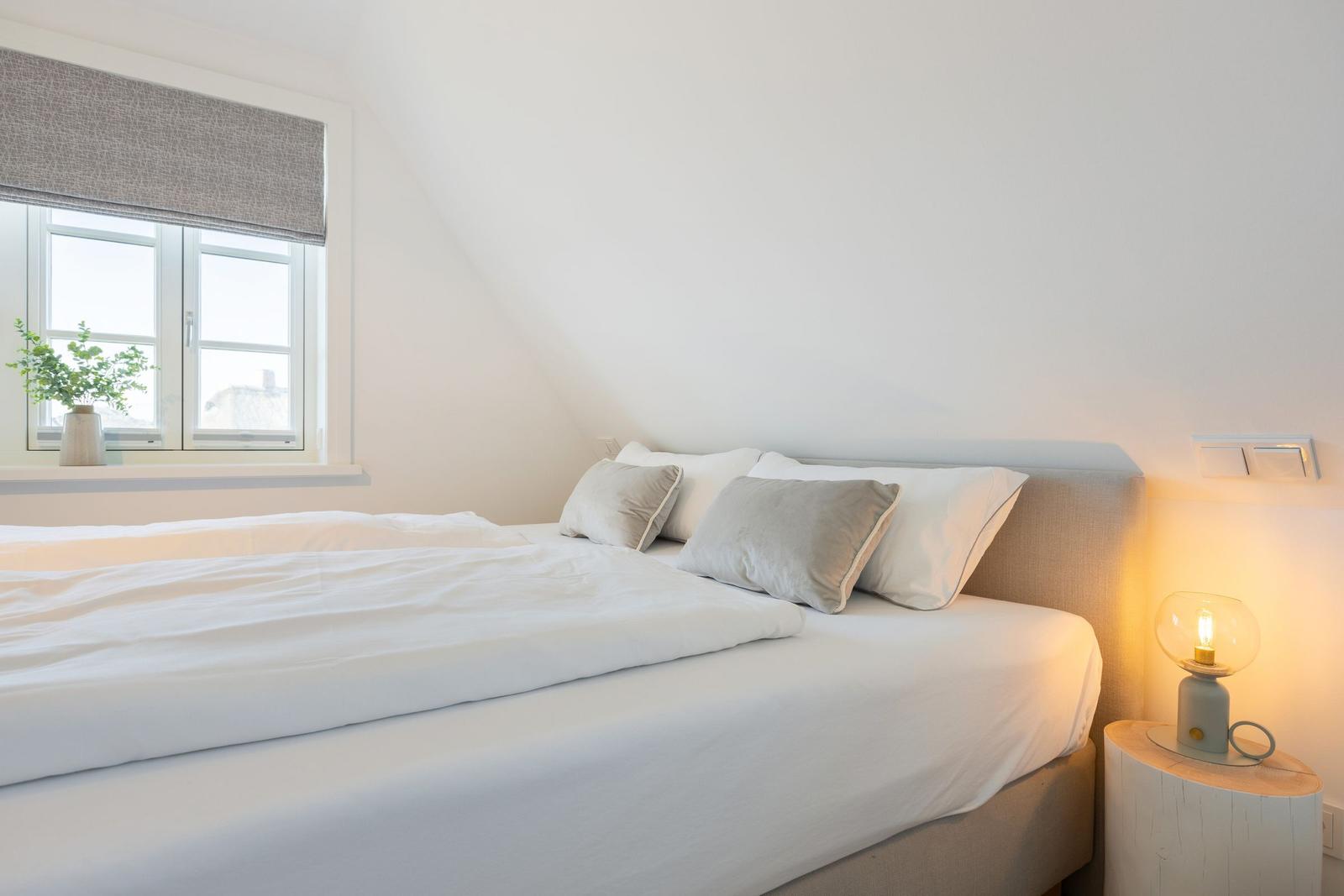 Bedroom with bed, window, and nightstand with lamp.