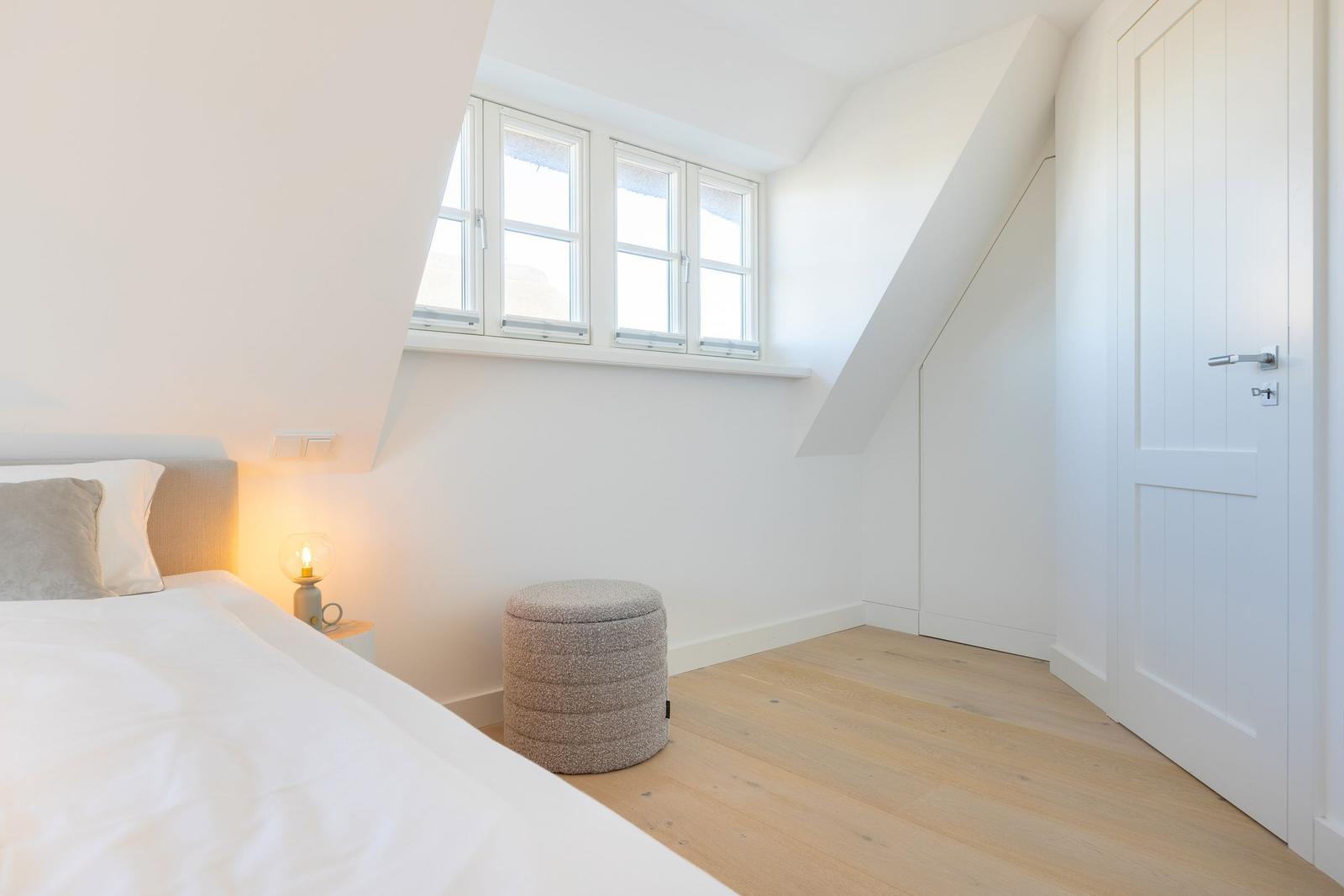 Bedroom with sloped ceiling, windows, and bed.