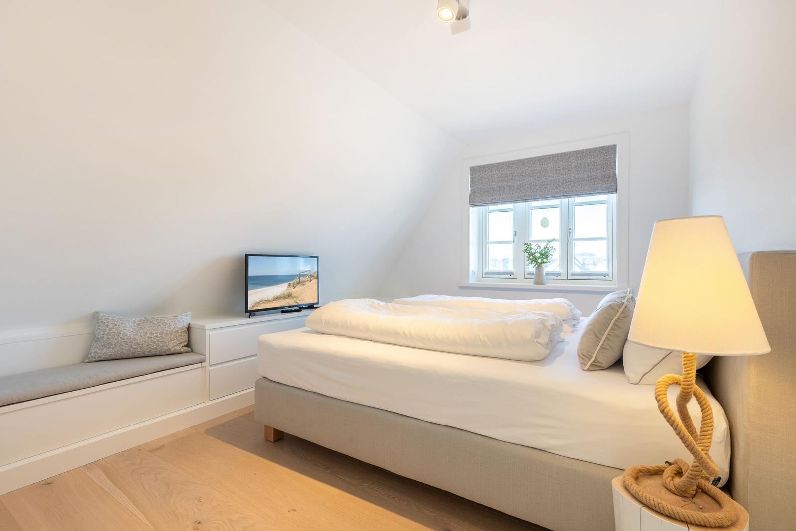 Bedroom with bed, window, and TV.