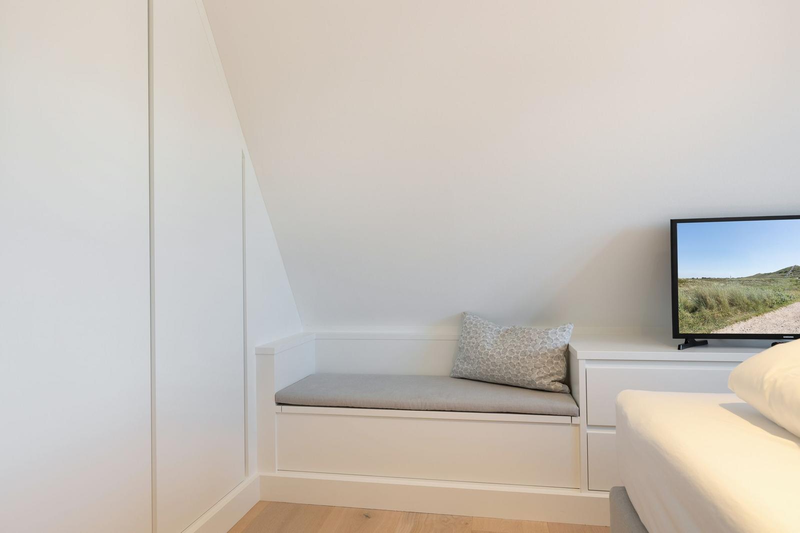 Bedroom with seating, TV, and closet.