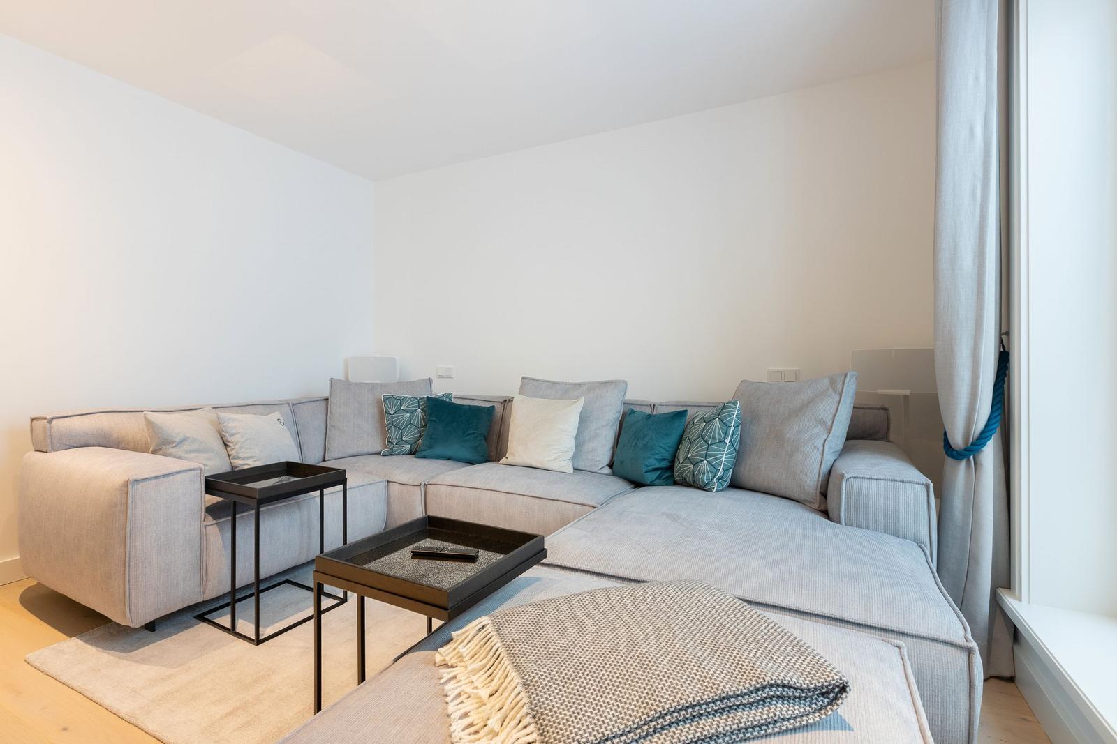 A living room with a large gray sectional sofa and two black tables.